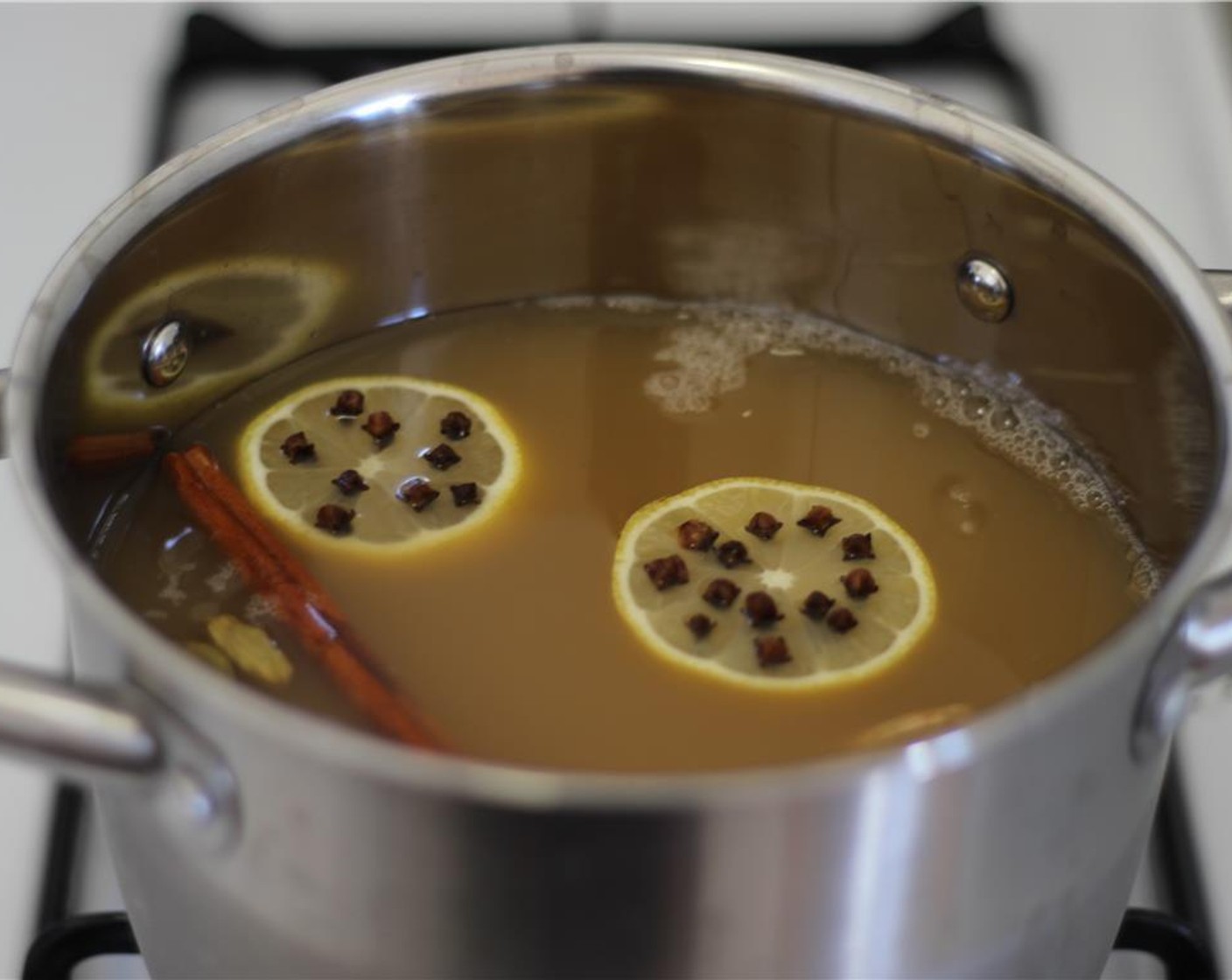 step 4 Add clove-studded lemon, Ground Allspice (1 dash), Whole Cardamom Pods (10 pieces), and sliced fresh ginger.