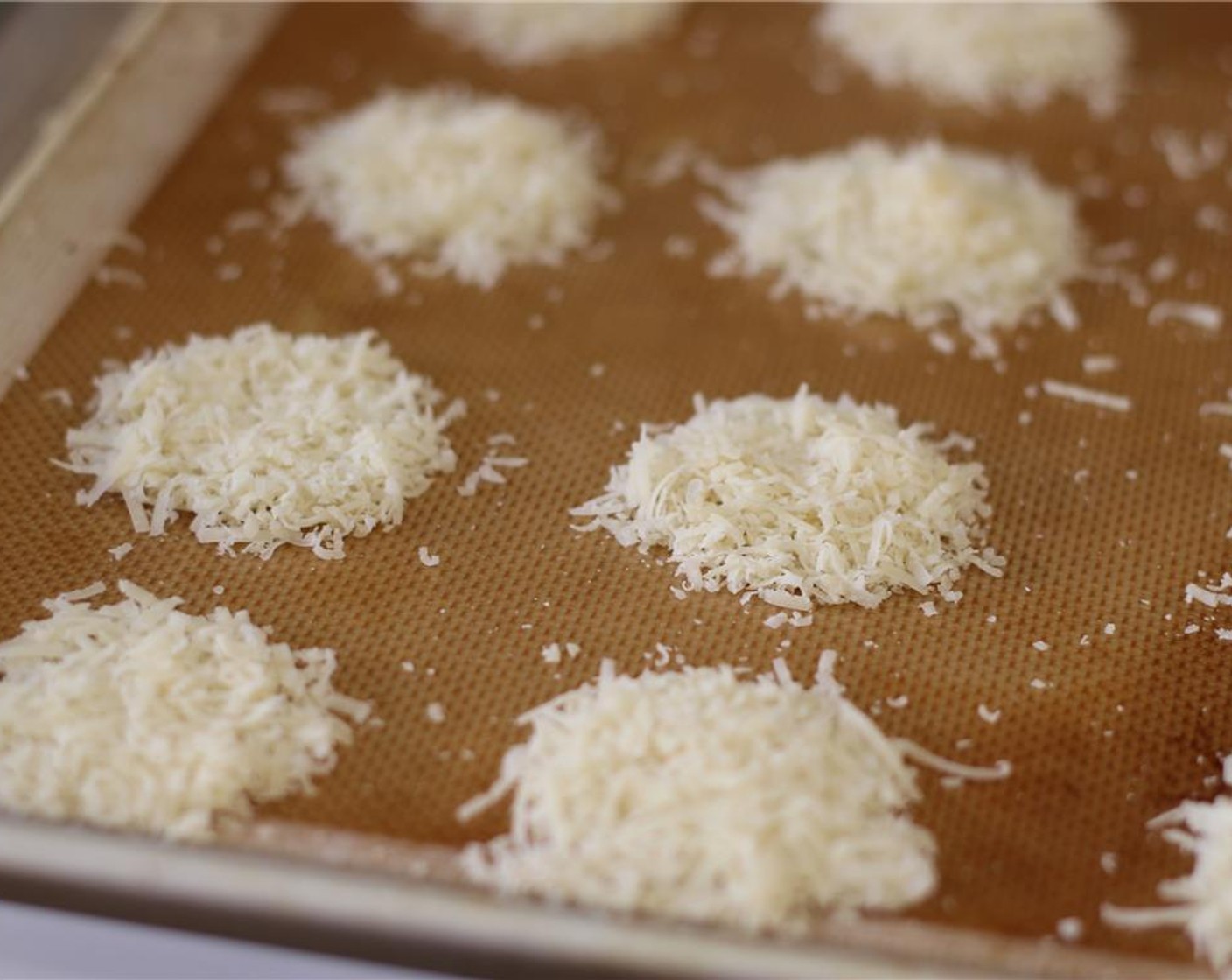 step 5 Scoop a tablespoon of grated parmesan onto the baking mat and arrange in a circle. Repeat with the remaining parmesan, leaving 1-inch between the circles.