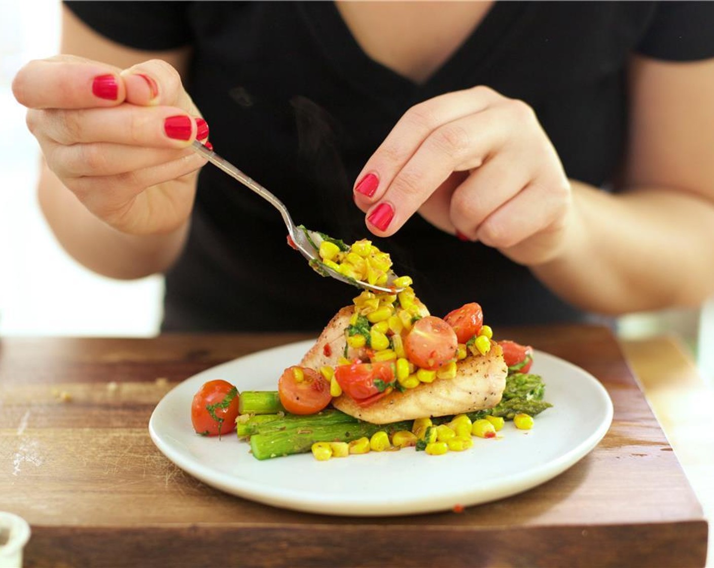 step 16 On the center of two plates, arrange half of the asparagus spears, facing the same direction. Place a generous amount of the succotash on top of the asparagus. Stack two pieces of the salmon on top of the asparagus at an angle and top with the green onions.