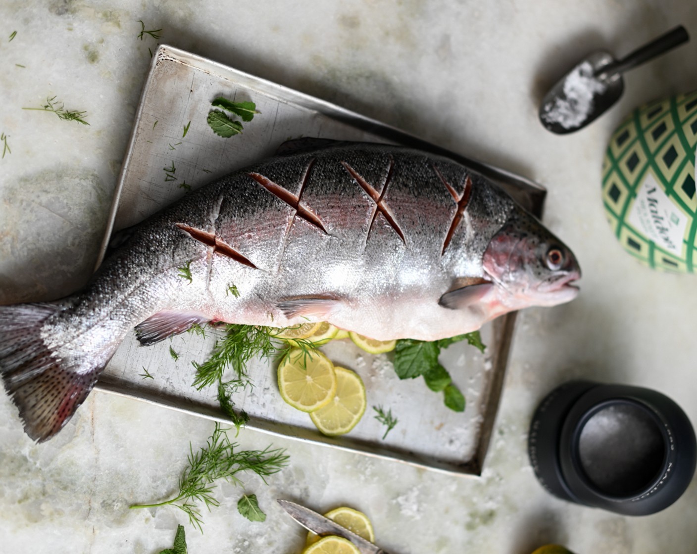 step 3 Stuff the fish with the Fresh Mint (4 sprigs), Fresh Dill (4 sprigs), and Lemons (2) and lay it flat on a lined baking sheet.