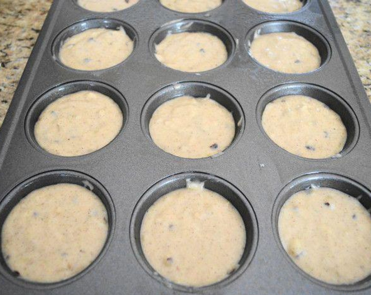 step 5 Use a heaping 1/4 cup to evenly distribute the batter among the 12 wells in the prepared muffin pan. Get the pan into the oven for them to bake for about 15 minutes. A toothpick inserted in the center should come out cleanly. Take them out and let them cool in the pan for a few minutes.
