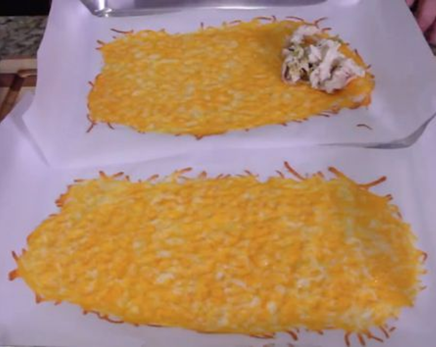 step 6 When the cheese is ready, remove from the oven and spoon the Chicken and Green Chili mixture into the Cheese near the edge that is closest to you. Roll the cheese carefully over the chicken to make a solid “tortilla”-style roll.
