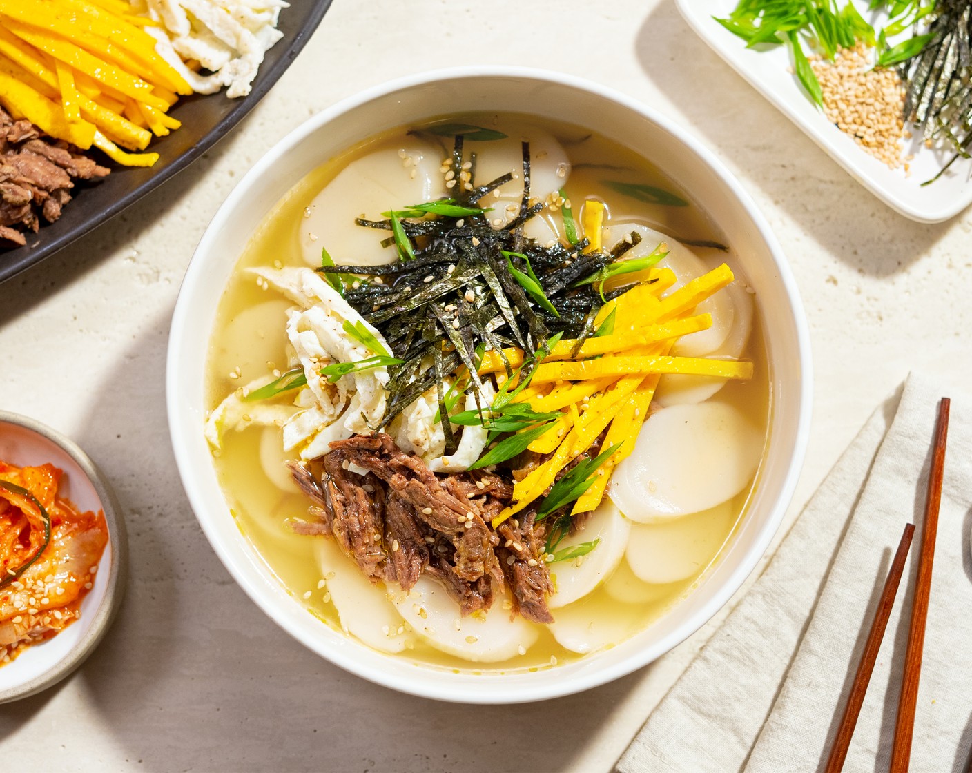 step 10 Bring the broth to a boil, then add the soaked Tteok Korean Rice Cakes (2 cups). Cook for 2-3 minutes or until the rice cake floats up. Serve with Toasted White Sesame Seeds (1 tsp), Nori Sheets (5), and Kimchi (to taste).