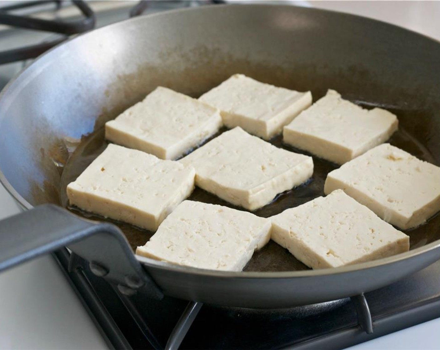 step 9 Add the tofu to the hot pan and let them sear for 5 minutes until the bottom of the tofu creates golden crust.