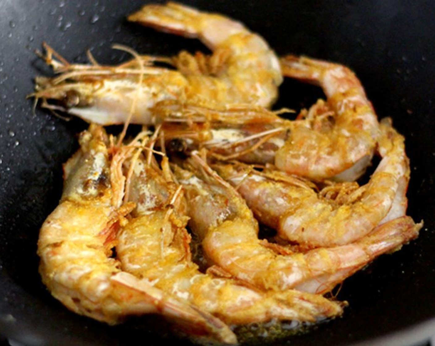 step 9 Heat up 3 tablespoons of garlic oil in a wok or deep skillet on high heat until smoking. Lay the shrimps flat on one side in the wok/skillet to fry, then don’t move them. Once the first side is blistered and crispy, add the Dried Chili Peppers (6).