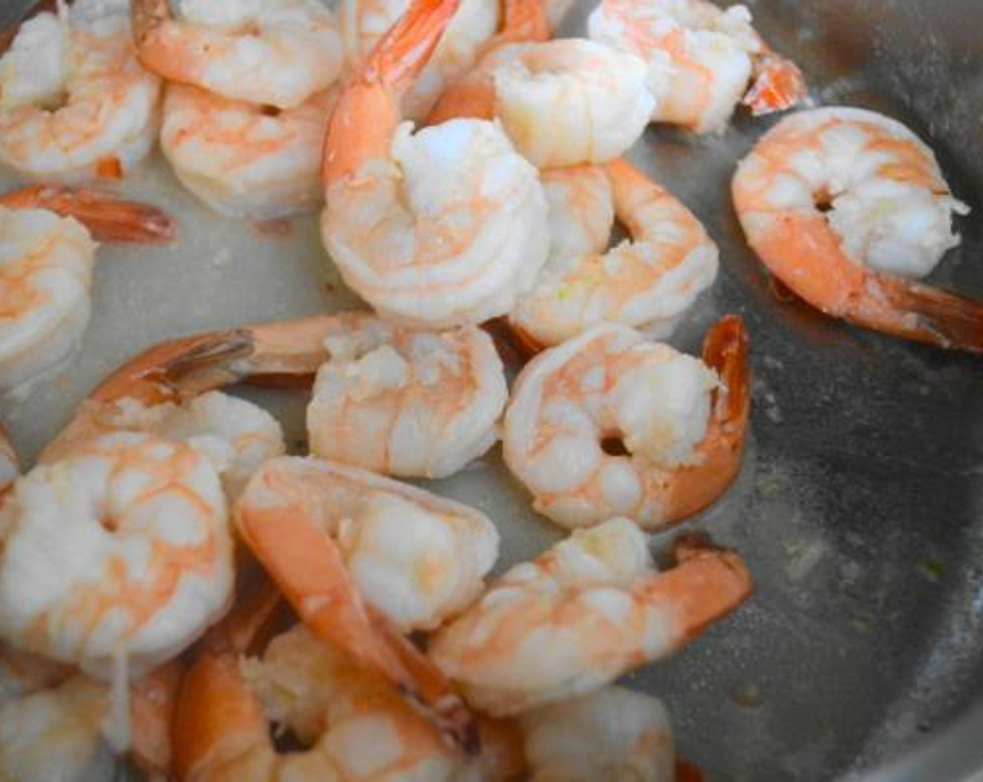 step 4 While the spaghetti cooks, prepare the shrimp. Heat the Coconut Oil (2 Tbsp) in a large skillet over medium-high heat. Add the Shrimp (1 lb) and cook them until they are pink and opaque. While they cook, season the shrimp with the Salt (1 pinch), Ground Black Pepper (1 pinch), and the zest and juice from the Lime (1). Once the shrimp are done, transfer them to a plate. Reserve the liquid.