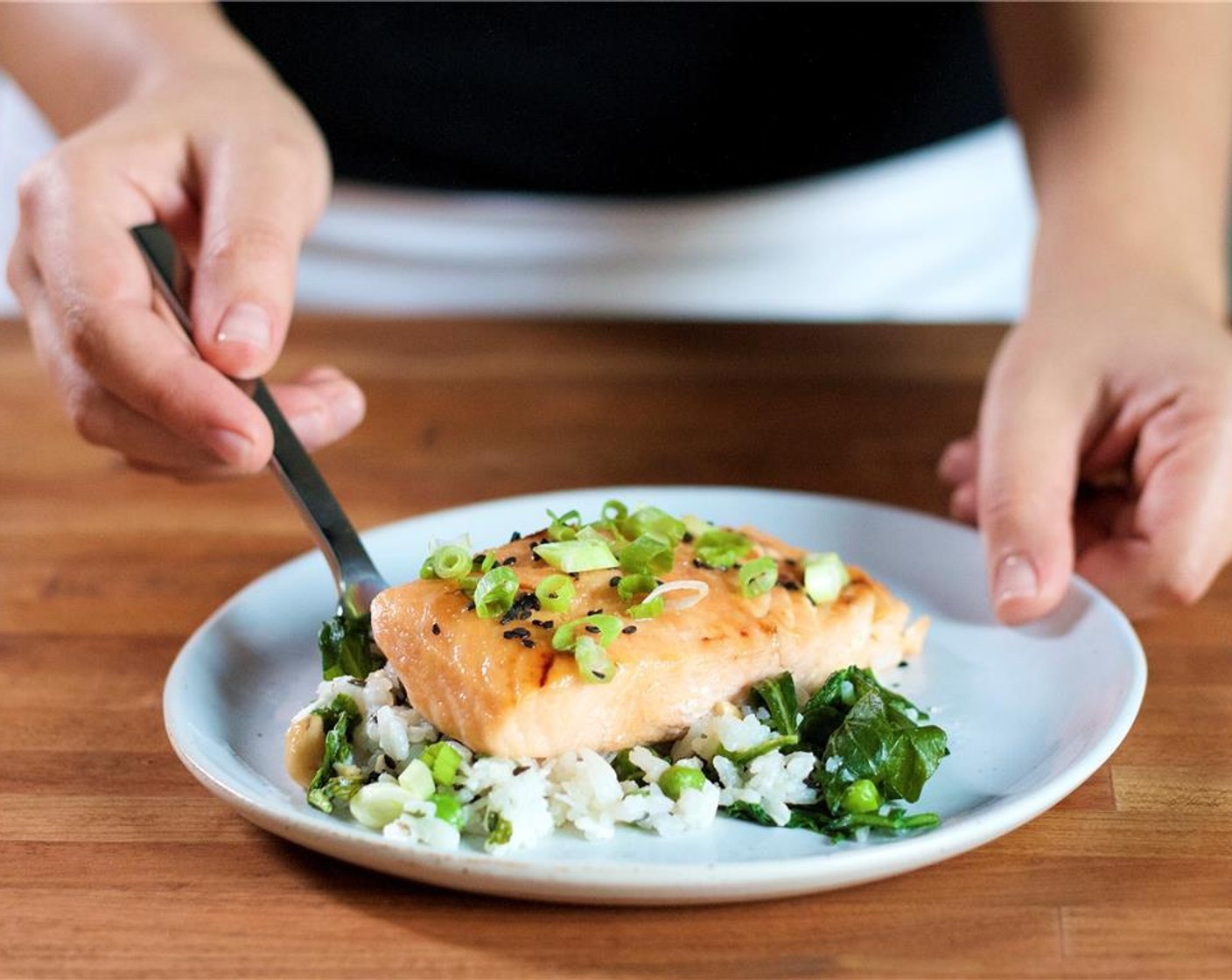step 12 Place the coconut basmati rice in the center of two plates. Place the salmon directly on top of the rice. Garnish by squeezing fresh lime juice over each plate, sprinkle with green onions and Black Sesame Seeds (1 tsp).
