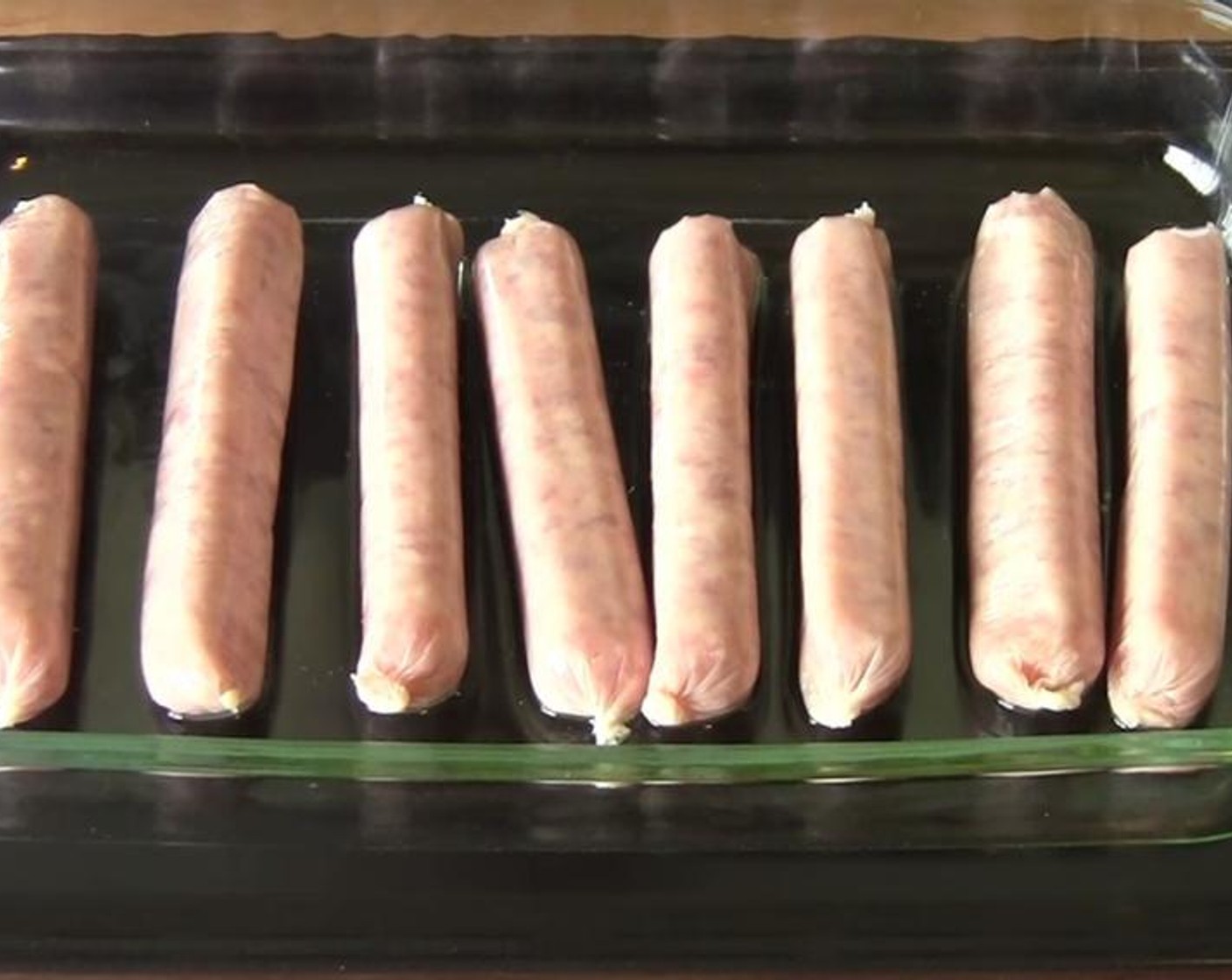 step 5 Place Sausages (8) into the oil in the baking dish. Place the dish back into the oven for ten minutes. Flip the sausages over after five minutes.