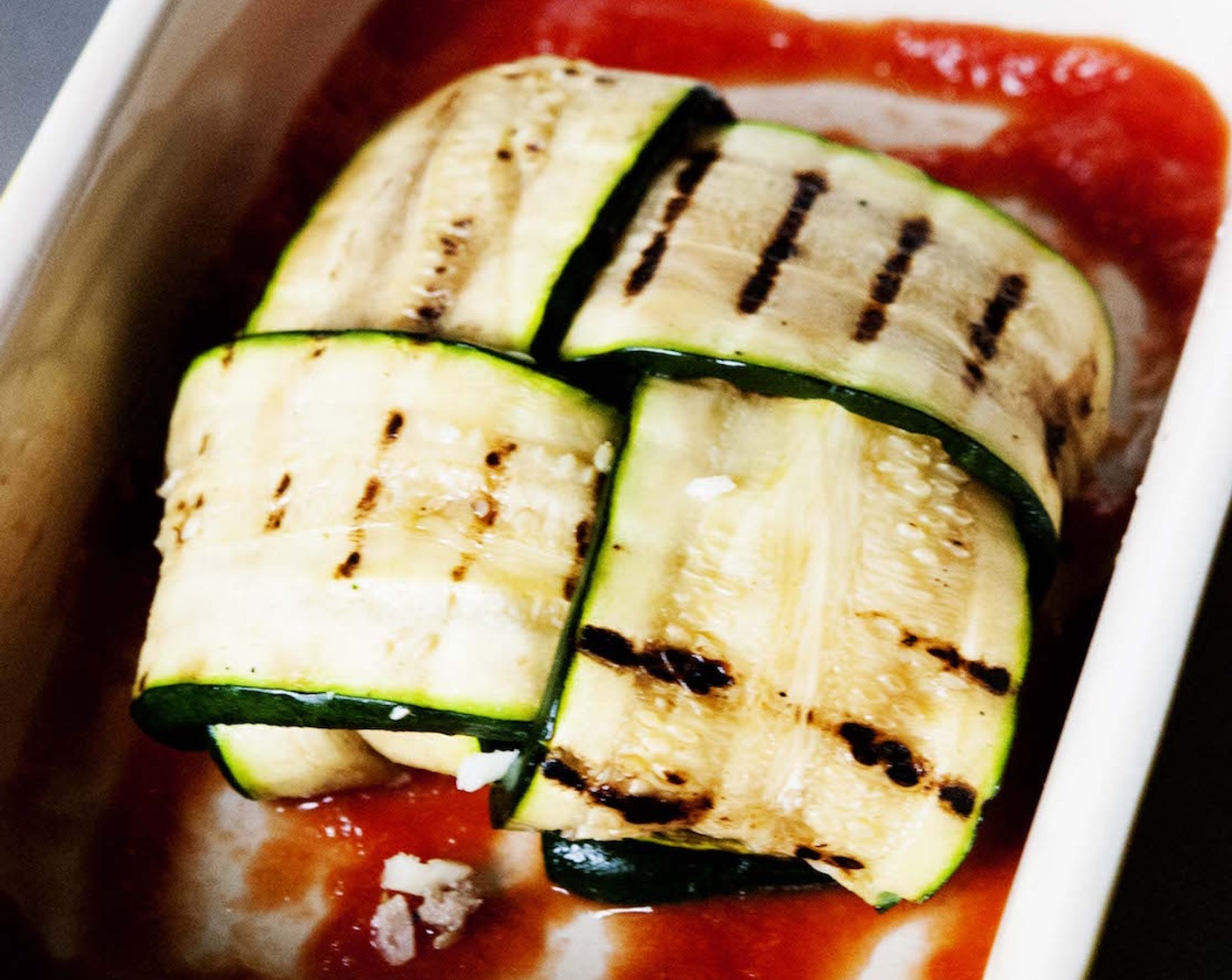 step 7 In a baking dish, ladle some Tomato Sauce (1/4 cup), and lay the stuffed zucchini pocket on top.