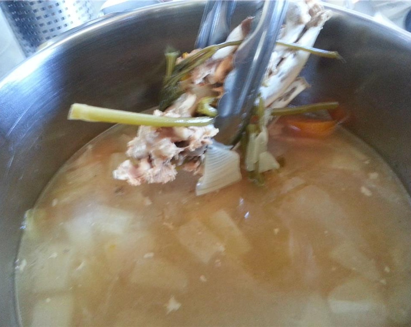 step 13 With a pair of tongs, remove any of the big pieces from the stock, so it is less of a mess when you strain.