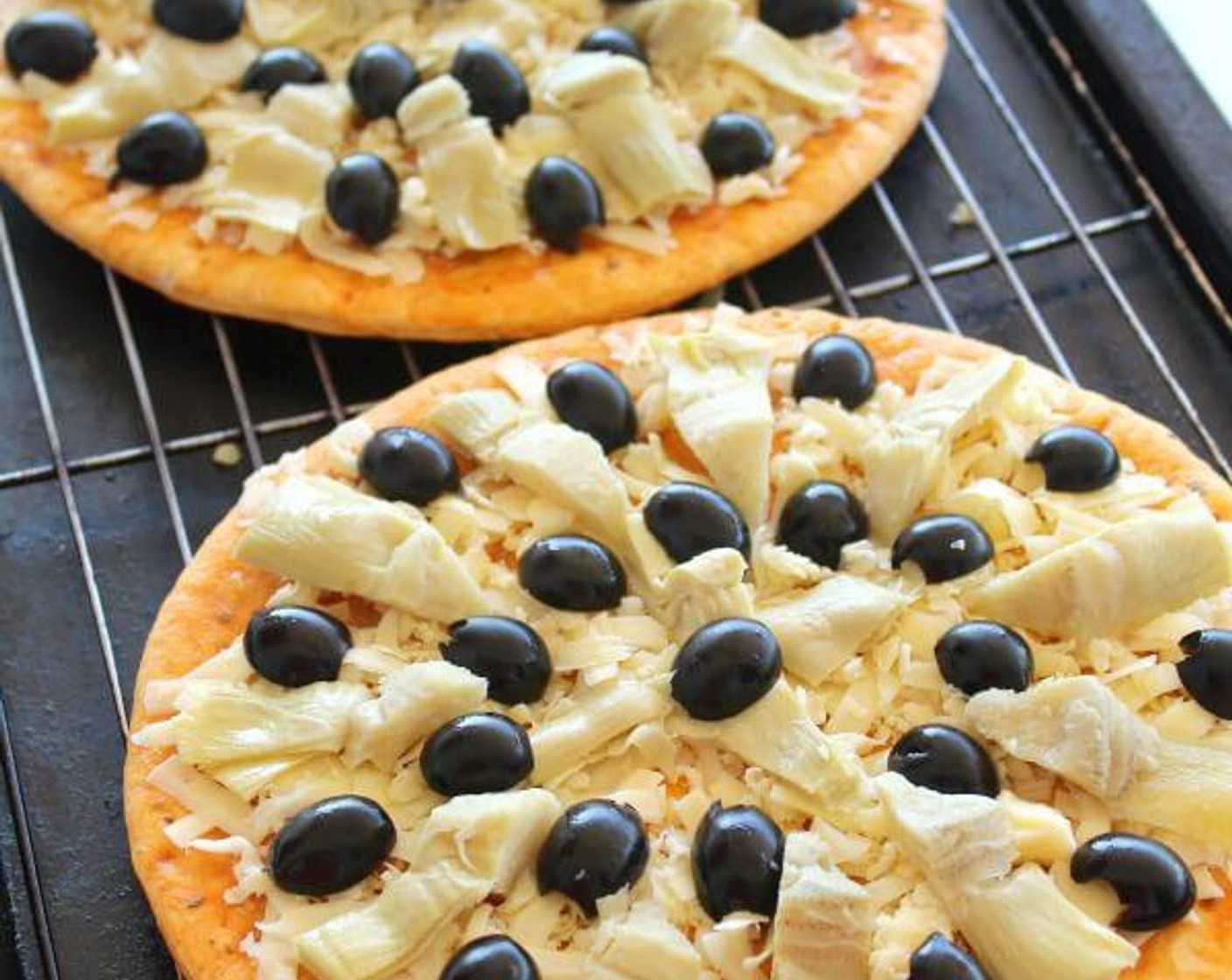 step 2 Place the Prepared Pizza Crusts (2) on a baking sheet with a grill rack. Layer the Mozzarella Cheese (1 cup), then the Artichoke Hearts (1 cup), and Black Olives (1 2/3 cups).