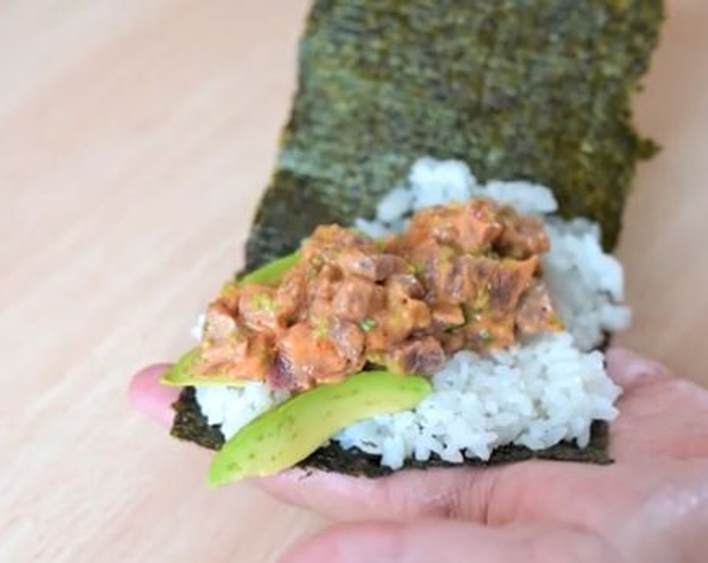 step 3 Extend half of the cooked Japanese Rice (3 Tbsp) over half of a Nori Sheet (1 sheet). Add Avocados (to taste) and the tuna mixture. Take the bottom end of the nori sheet and bring upwards to roll into a cone. Use a grain of rice to stick the nori together where it meets.