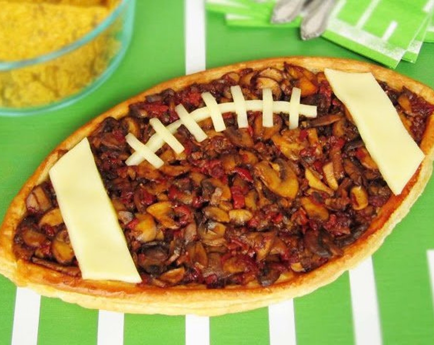 step 18 Cut 3 thin slices of White Cheese (3 slices) from a block of cheese then cut them into the desired shapes (or use rectangular cheese slices). Use the cheese slices to make the laces and stripes on the football. Set on the hot tart to melt the cheese slightly. Serve hot.