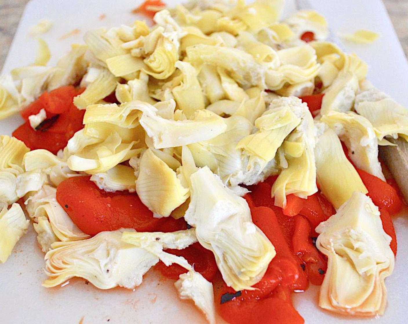 step 3 Then heat up the Olive Oil (1 dash) in a large, deep skillet over medium-high​ heat. Cook the Jarred Roasted Red Peppers (1 jar) and Artichoke Hearts (1 can) in it for just a couple of minutes.