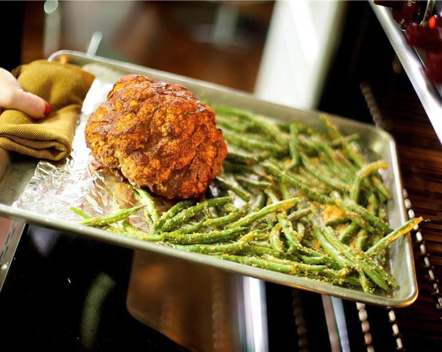 step 7 After the cauliflower has roasted for 30 minutes, remove the pan from the oven. Pour the green beans onto the same baking sheet pan with the cauliflower and return both into the oven.