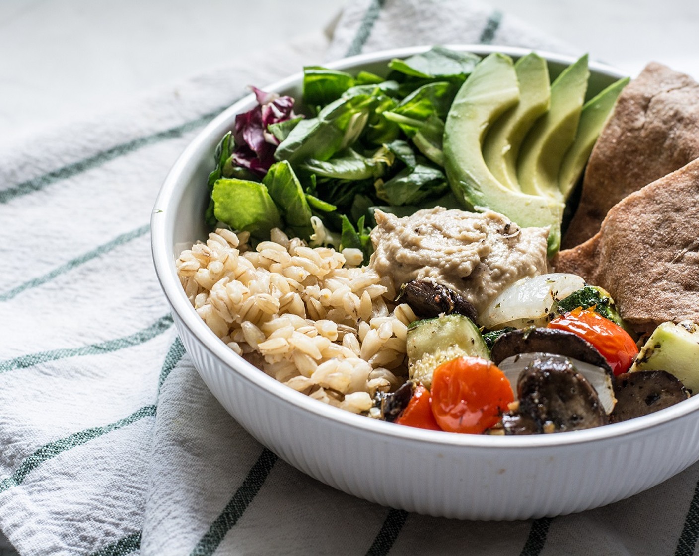 step 8 Divide chopped Salad Greens (1 cup) between 2 large shallow bowls, then add cooked barley, roasted veggies, Hummus (1/4 cup), and Avocado (1/2). Drizzle with dressing of choice if desired. Serve with pita or naan bread.