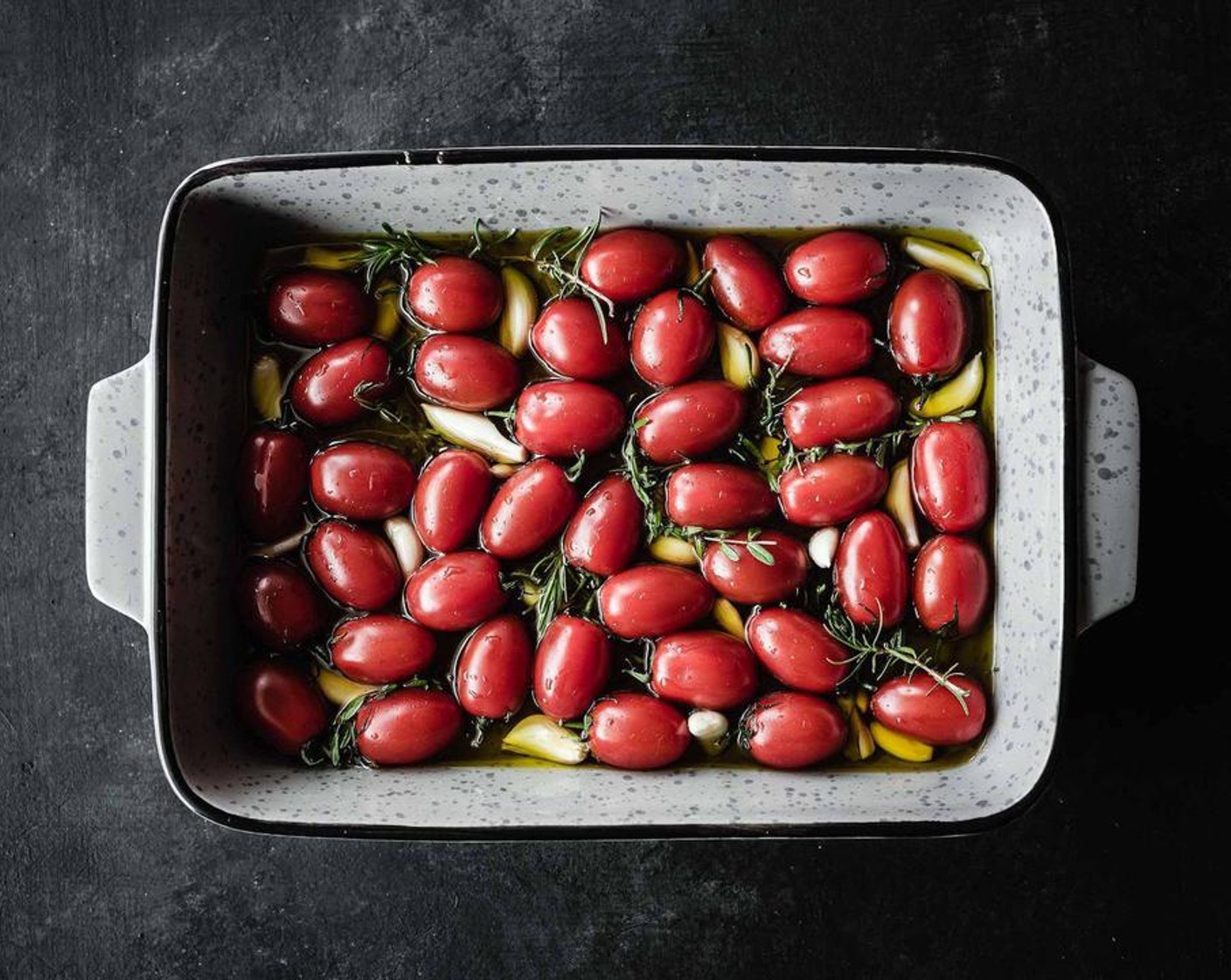 step 2 Fill a baking pan with whole Cherry Tomatoes (3 cups) - add Extra-Virgin Olive Oil (1/2 cup), Garlic (3 cloves), Fresh Rosemary (3 sprigs), and Fresh Thyme (5 sprigs) to the pan and sprinkle the pan contents generously with Salt (to taste).