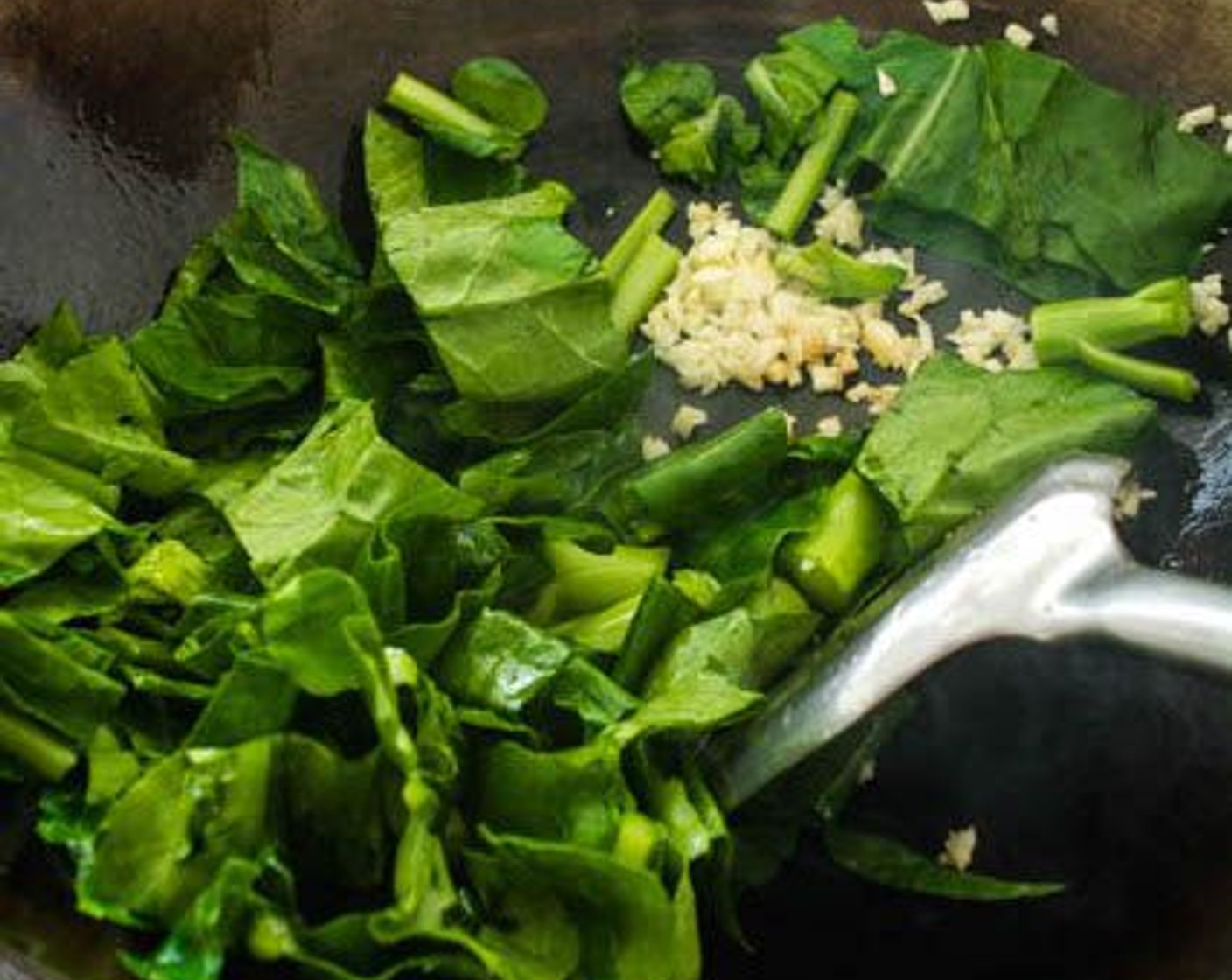 step 8 Add Cooking Oil (1 Tbsp) to the wok, followed by the Garlic (3 cloves), and Chinese broccoli. Stir-fry until the stems of the Chinese Broccoli are slightly soft, 1 - 2 minutes.