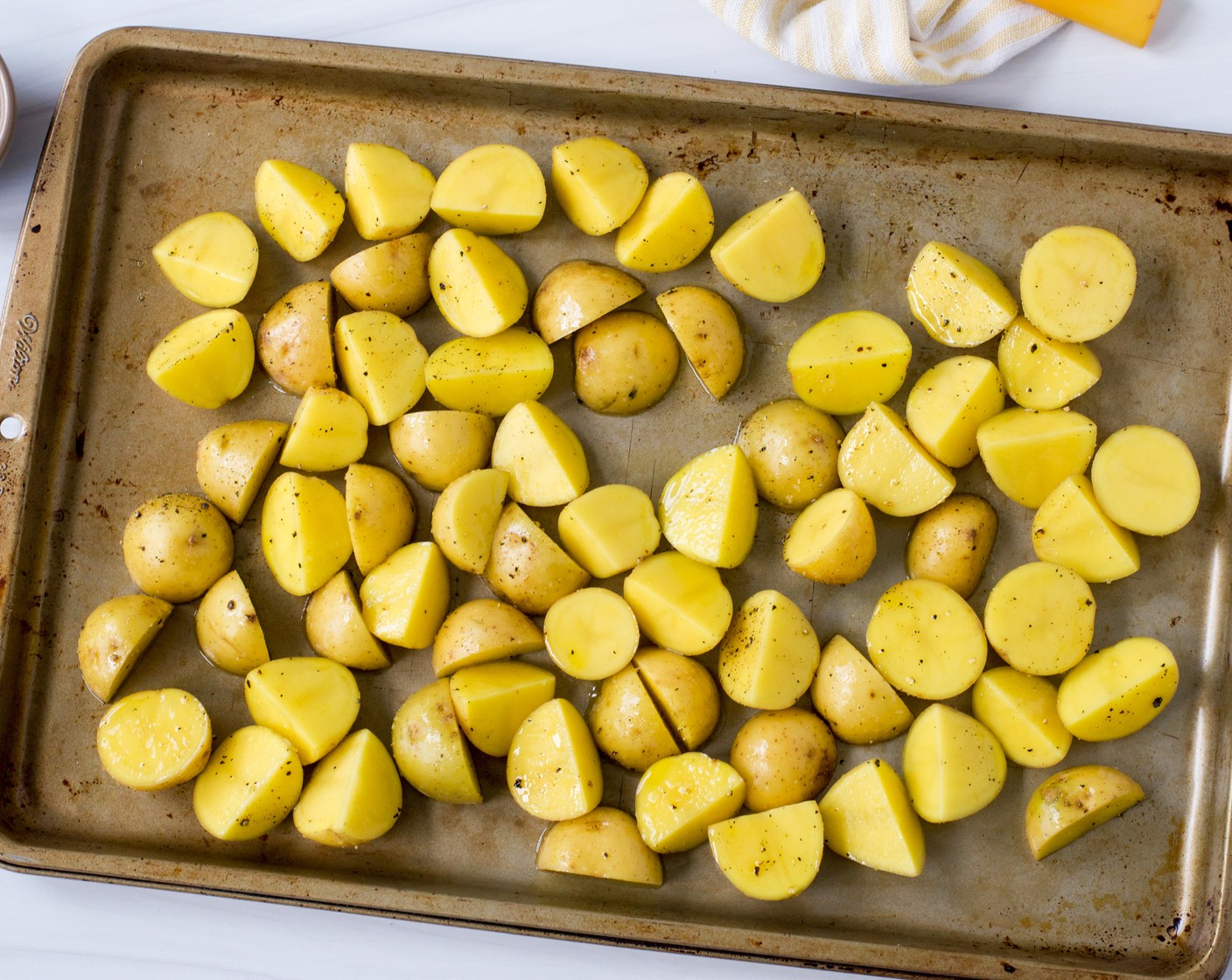 step 2 Halve or quarter the Baby Potatoes (1.5 lb) depending on their size and toss them in a large bowl with 2 Tbsp of Extra-Virgin Olive Oil (2 Tbsp), 1 tsp of the Kosher Salt (1 tsp), and ½ tsp of Freshly Ground Black Pepper (1/2 tsp). Arrange the potatoes in an even layer on a rimmed half-sheet pan.