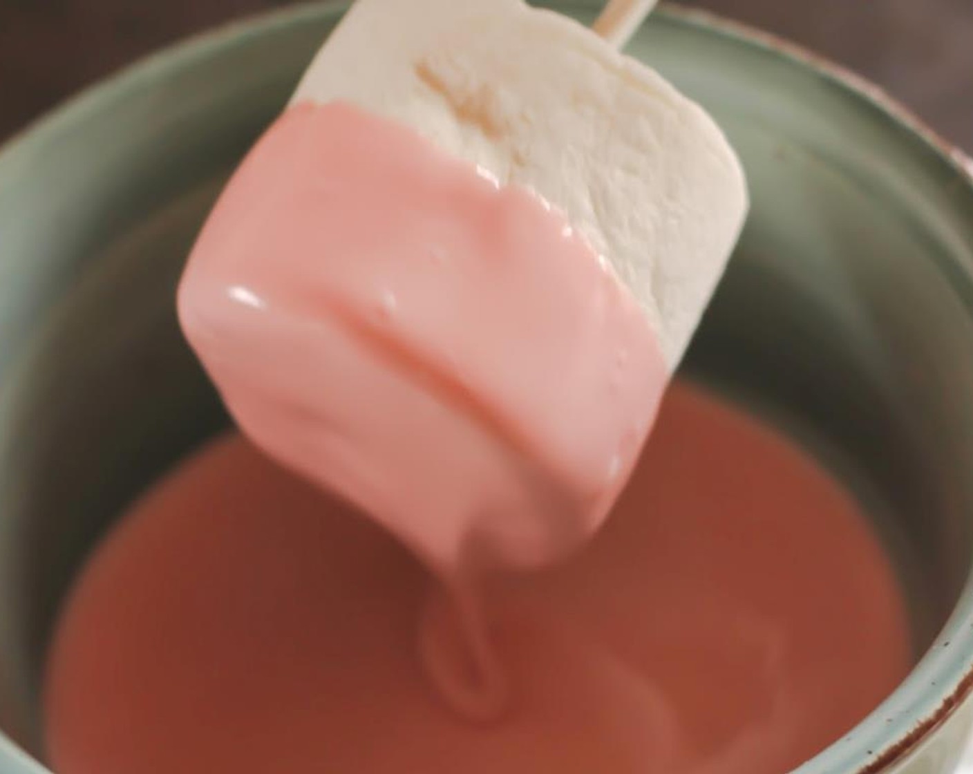 step 4 Place a popsicle stick into the middle of a marshmallow and dip halfway into the melted chocolate. Use a knife to help remove excess chocolate.