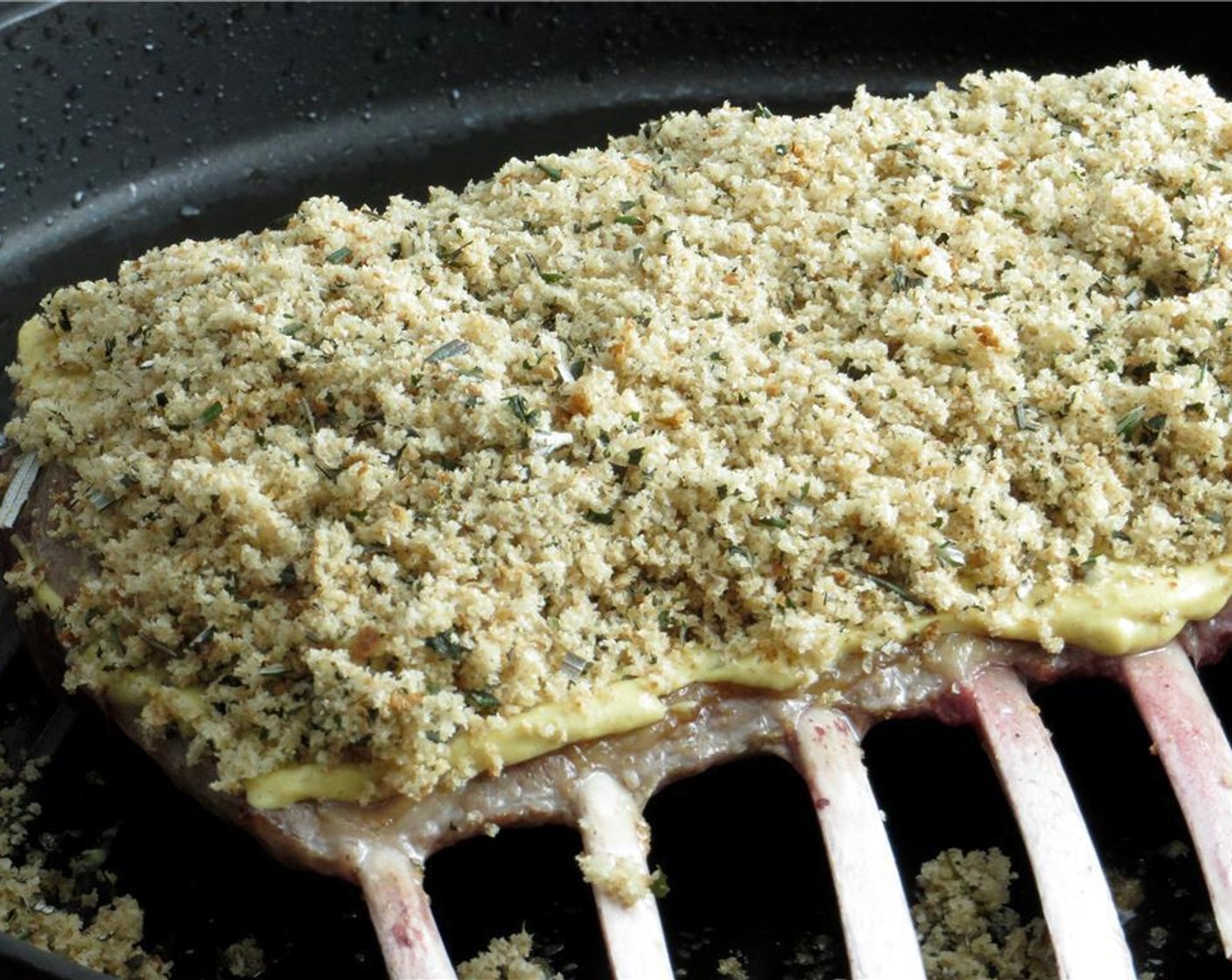 step 3 Flip lamb over, and cook for an additional minute. Remove from heat. Spread Dijon Mustard (1 Tbsp) on fattier side of rack of lamb. Top dijon mustard with bread crumbs, pressing down slightly to adhere.