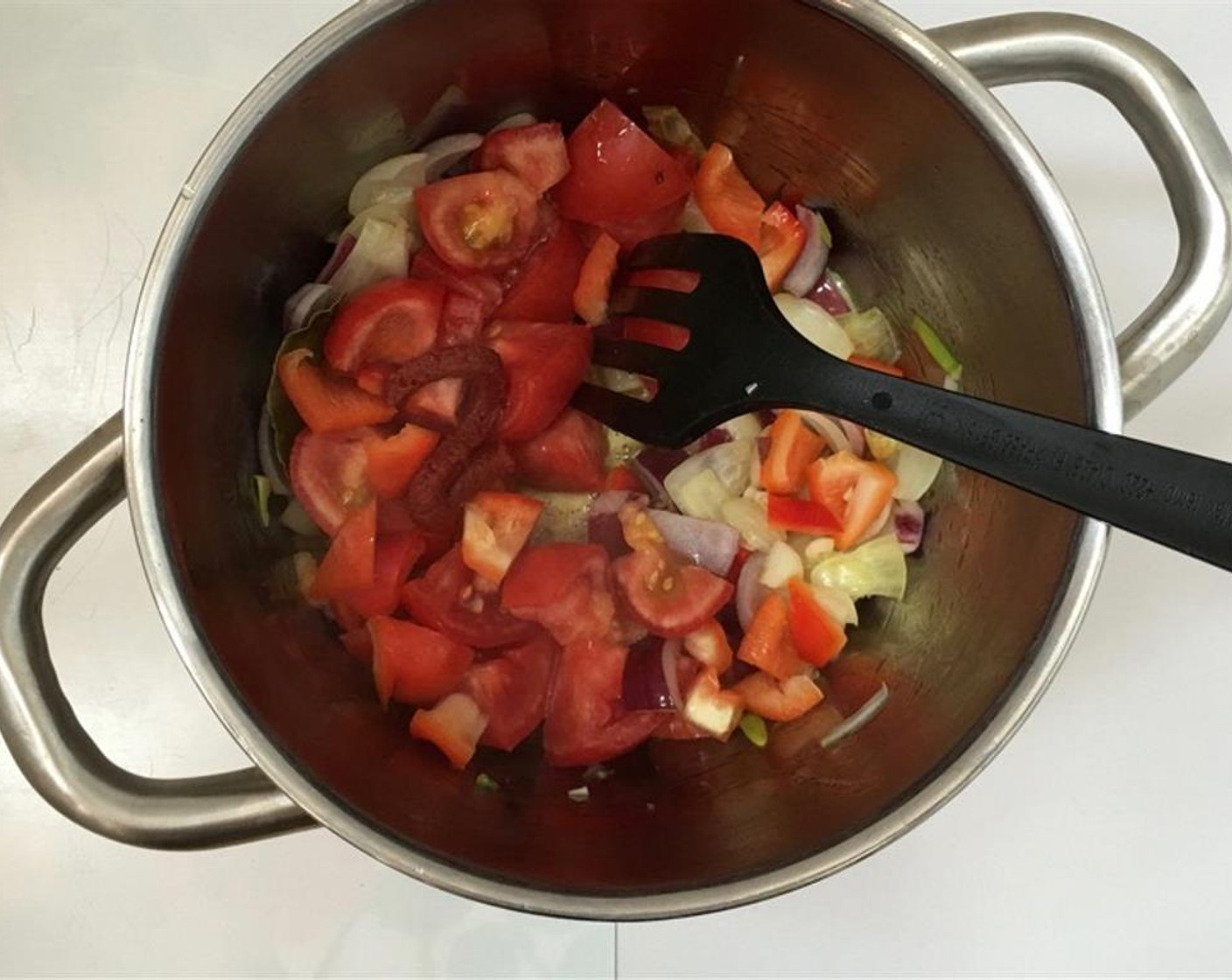 step 2 Place the pan over medium-high heat and stir well. Then roughly chop up the Tomatoes (2), Tomato Paste (1 Tbsp), and the Red Bell Pepper (1/2). Add it to the pan.