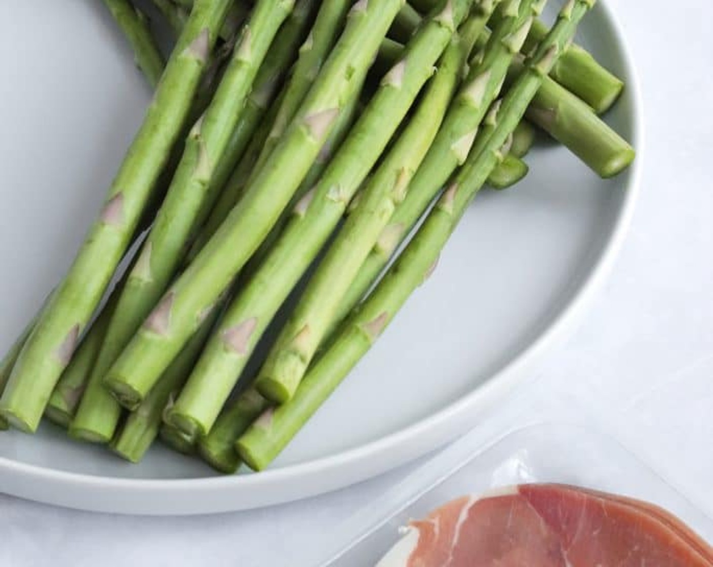 step 2 Trim the tough ends off of the Asparagus (3 cups). Take the Prosciutto (6 oz) slices and cut them in half horizontally so you have long strips to wrap.