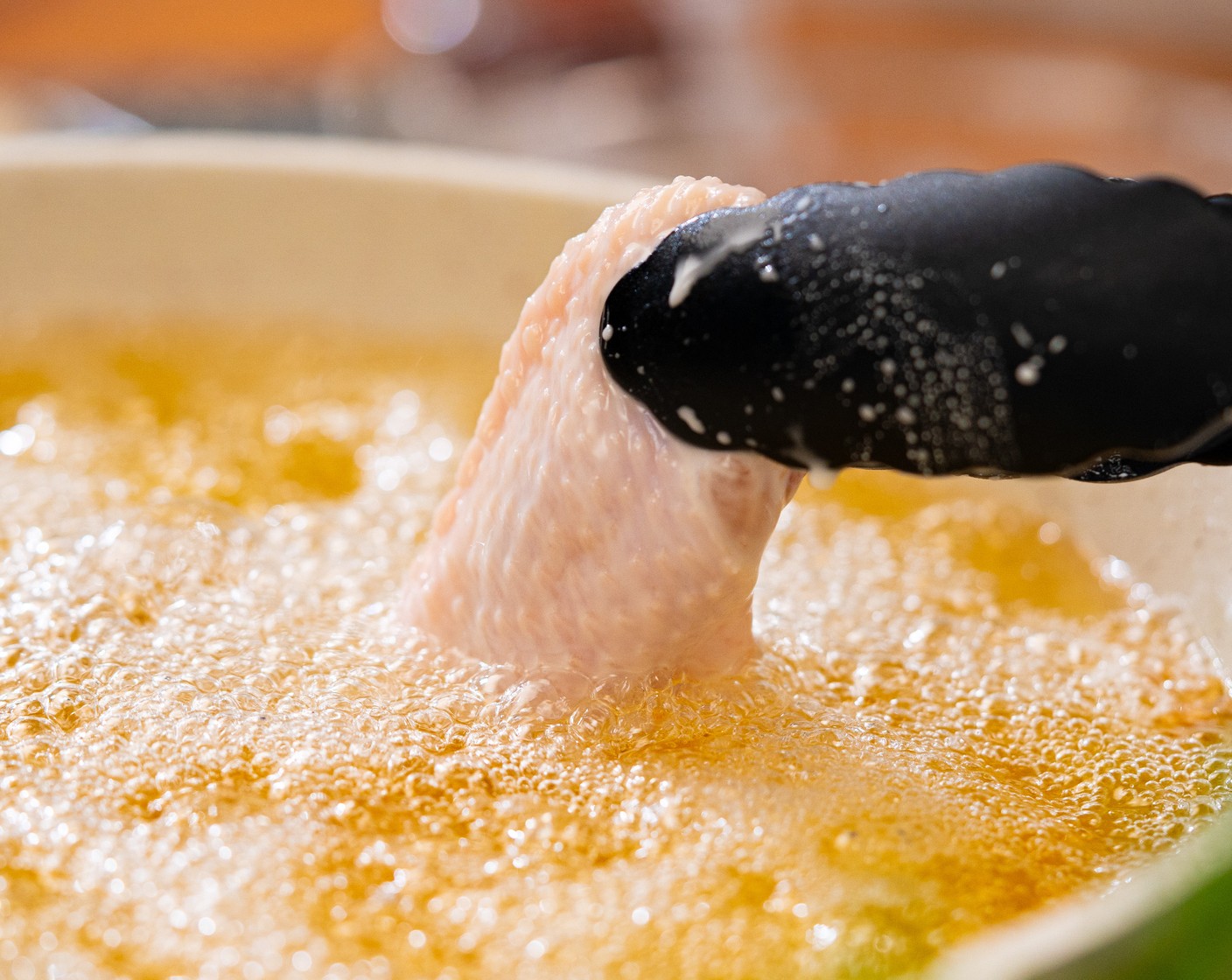 step 5 Whisk the batter to remix and add half the wings, tossing to coat. One by one, let the extra batter drizzle off the wings and place into the hot oil. Repeat until you have a single layer across the bottom of the pot. Cook for 6-7 minutes or until they turn a light golden brown - they will stick to the bottom at first, just let them cook for 30 seconds before trying to move them, and they should come up effortlessly.