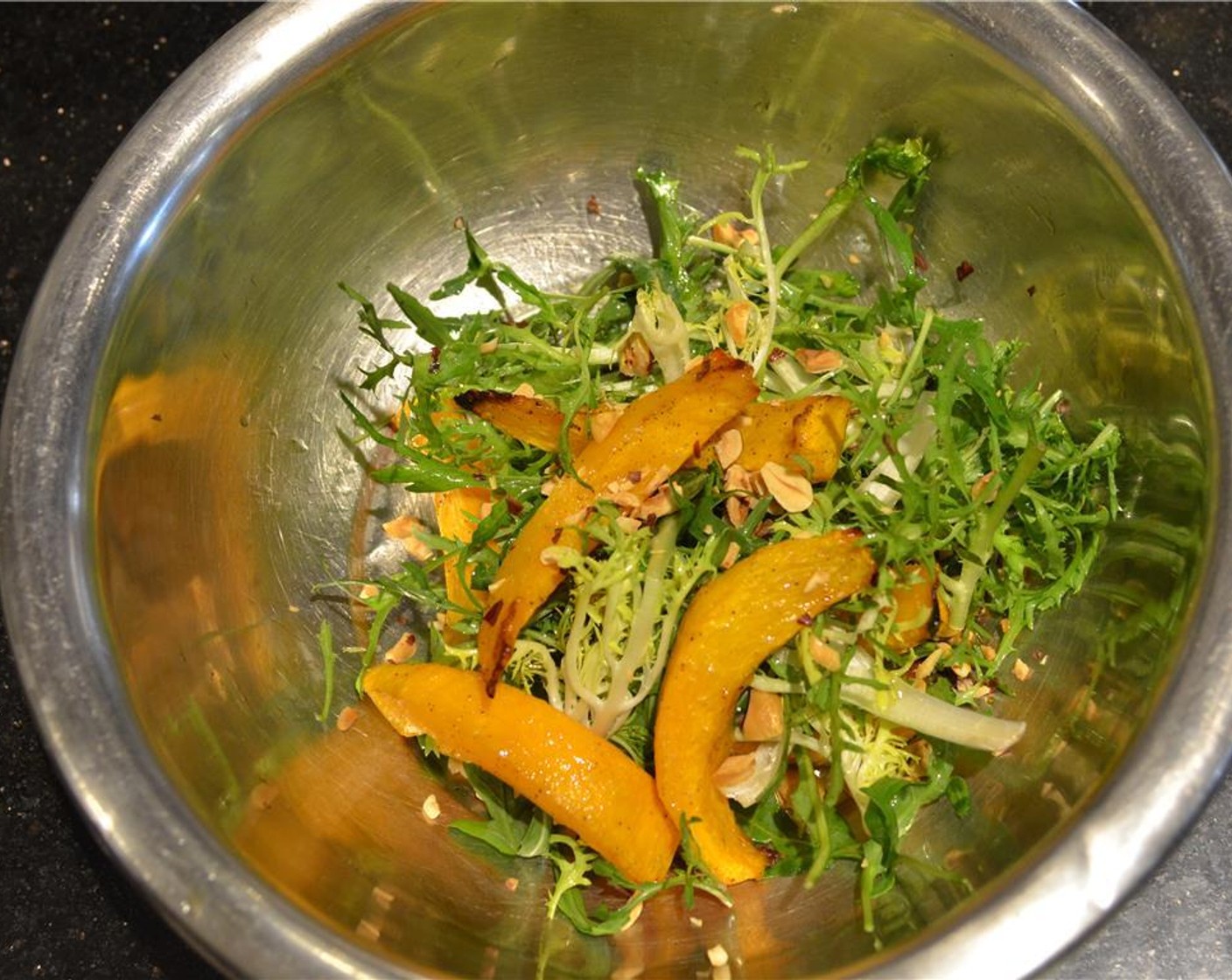 step 10 Lightly crush the Hazelnuts (1 Tbsp) and place them in a large mixing bowl with the Arugula (1 bunch), Curly Endive (1 handful), Pumpkin Seeds (1 Tbsp), and warm squash wedges.