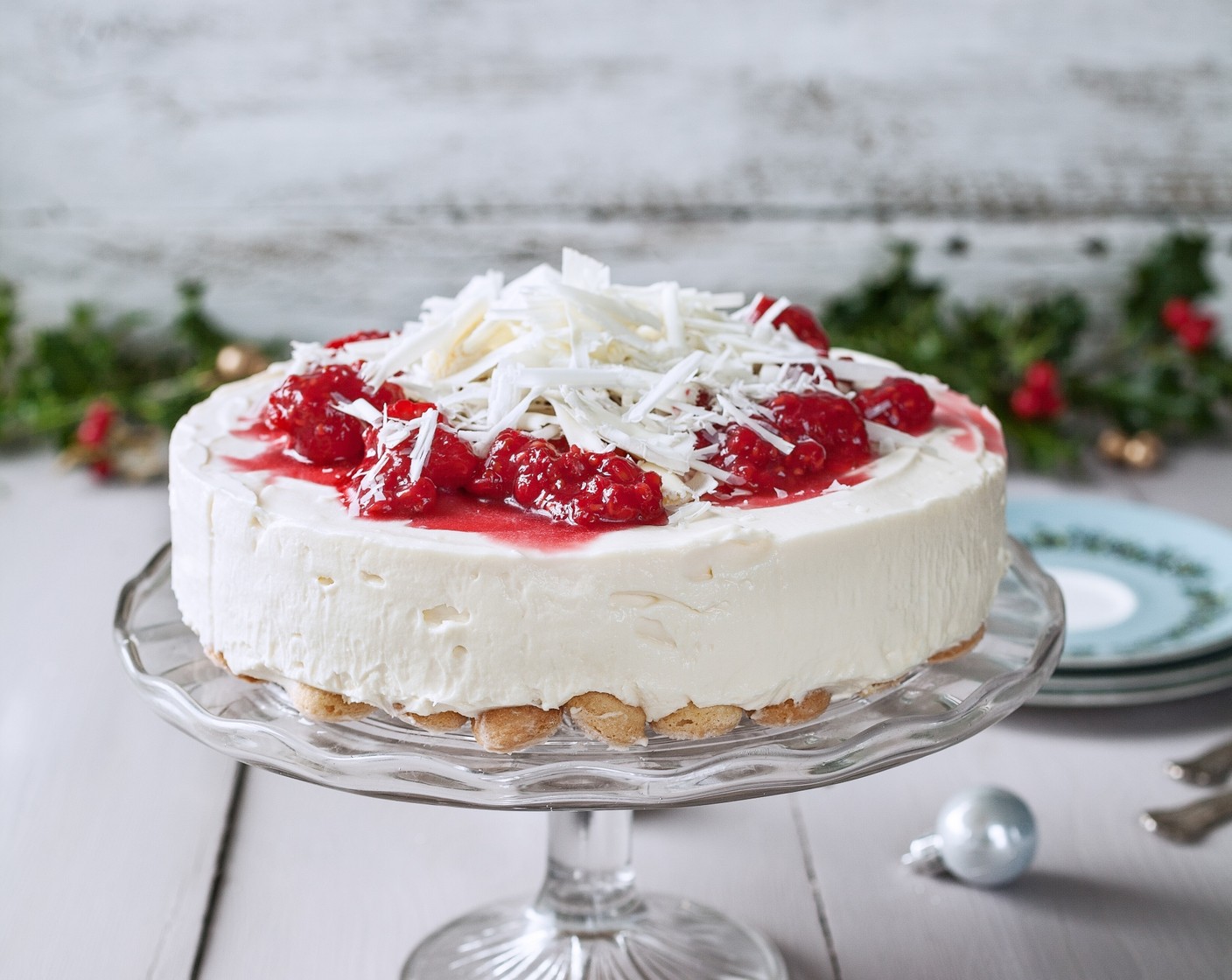 step 6 Carefully remove the cheesecake from the tin, then decorate the top with White Chocolate (2/3 cup) and a drizzle of Raspberry Sauce (3 Tbsp) to serve.