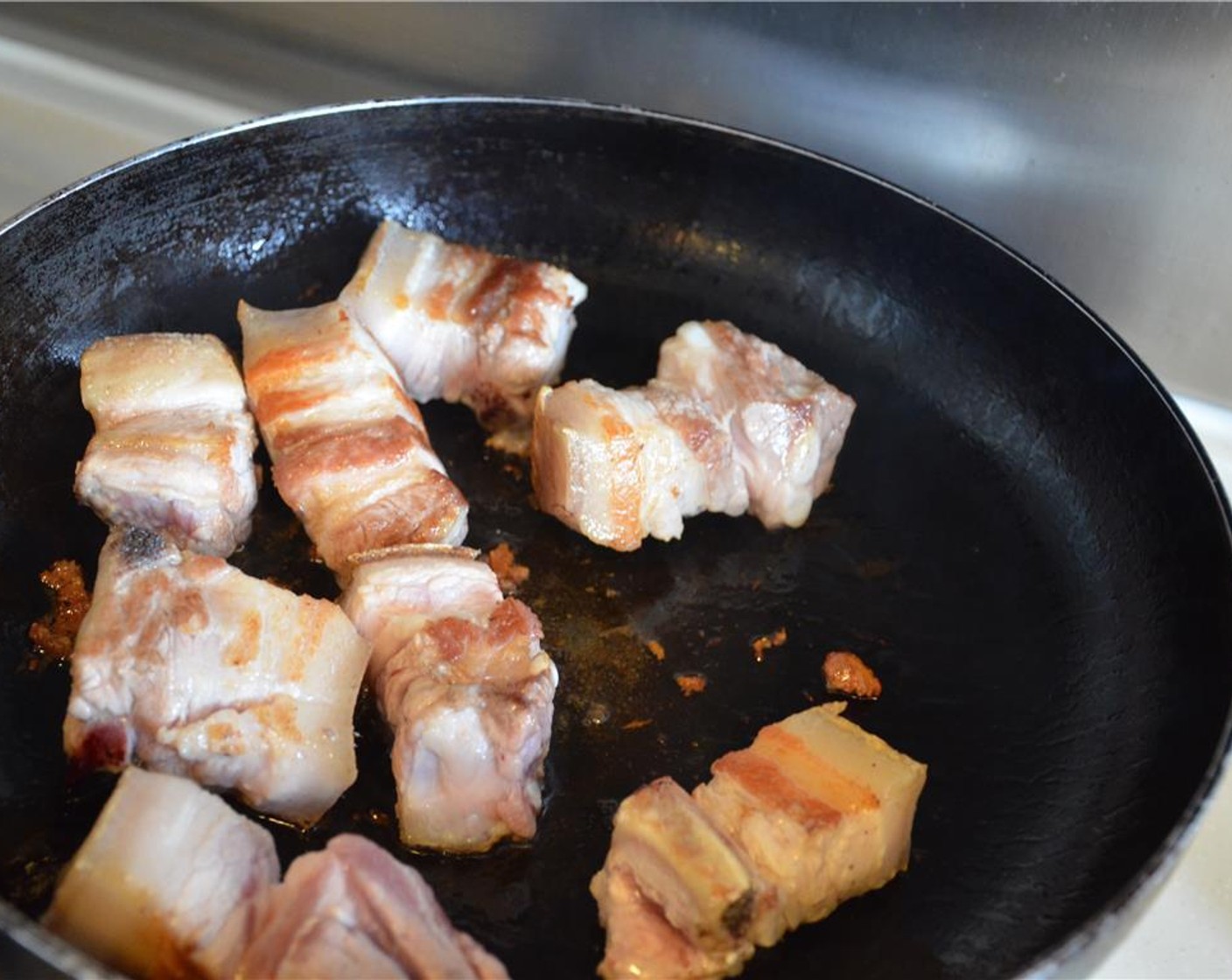 step 6 Heat a wok or cast iron pan over medium high heat and sear the pork belly for 5 minutes, making sure to evenly brown on each side. When nice and brown and plenty of fat has rendered, remove the pork and set aside. Drain fat from pan.