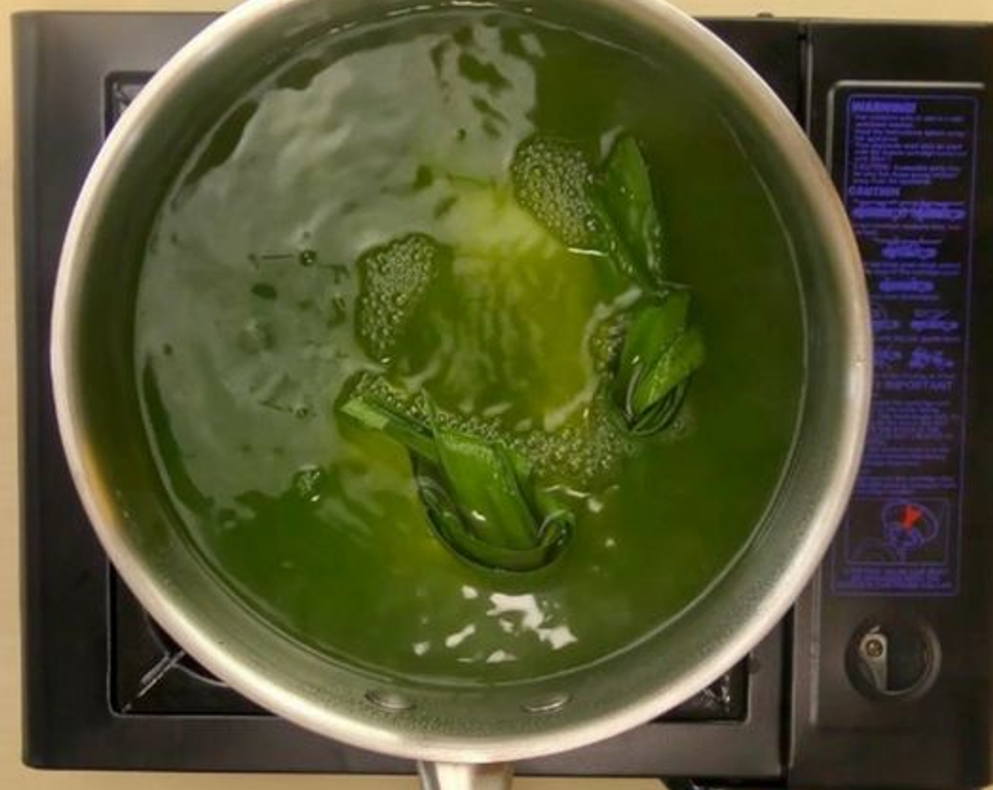 step 7 In a pot of water, add the blended pandan leaves and the remaining pandan juice. Then bring to a boil. Lightly put in the rolled dough balls and simmer until cooked whereby the dough balls float to the surface.