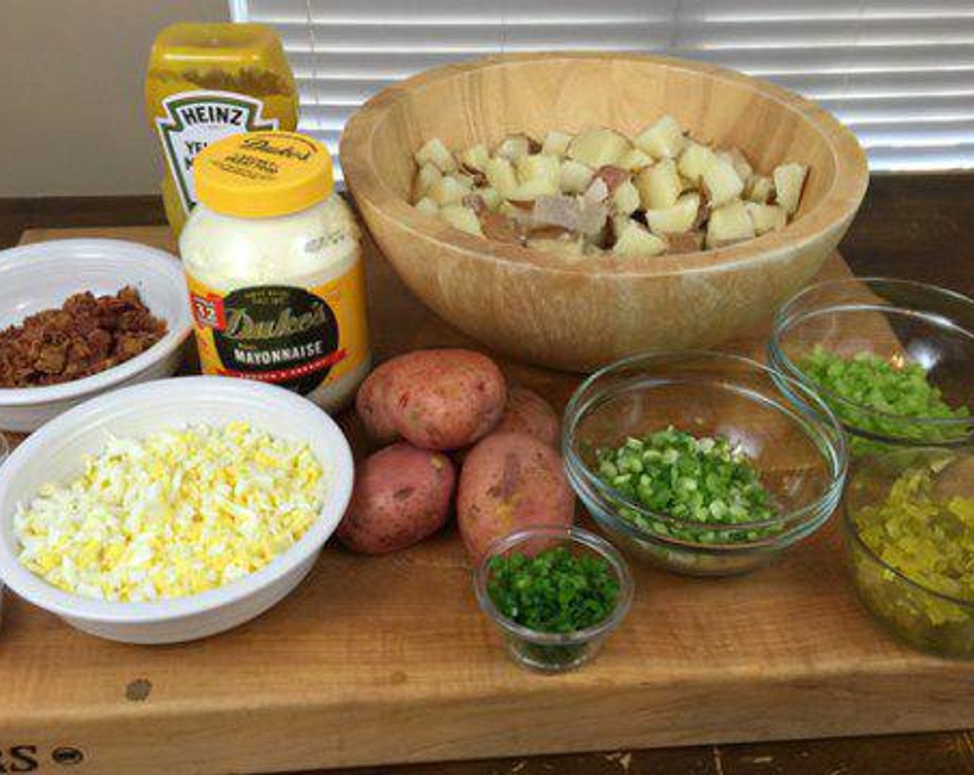 step 2 Combine Mayonnaise (2 cups), Yellow Mustard (1 Tbsp), Eggs (4), Pickles (1/2 cup), Scallion (1 bunch), Celery (1 stalk), Salt (1 tsp), Ground Black Pepper (1 tsp) in a separate bowl. Taste and add more salt and pepper if desired. Once combined fold dressing onto potatoes lightly until all potatoes are covered.