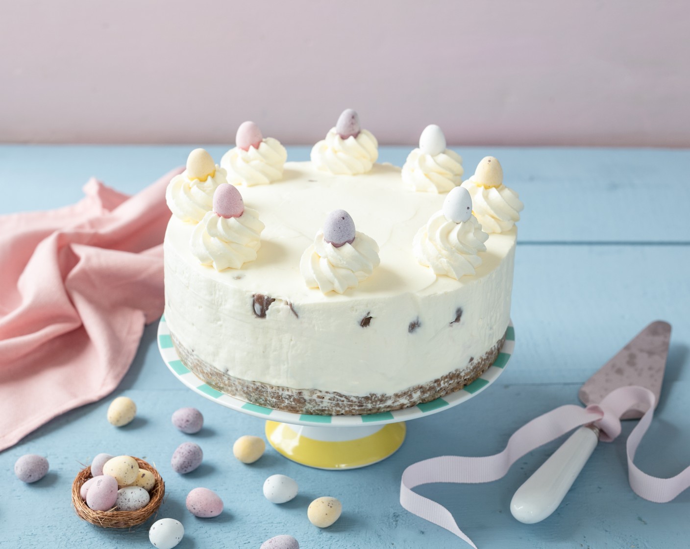 step 6 Carefully remove the cheesecake from the tin. Dollop the remaining whipped cream on top and use to hold the remaining Mini Eggs in place as decoration.
