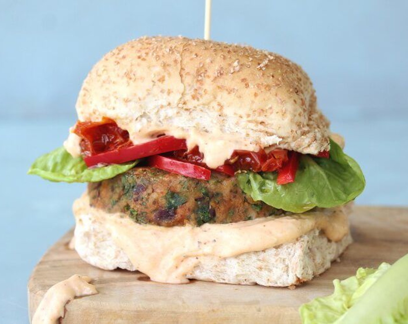 step 6 Top with the burgers, Sun-Dried Tomatoes (1/2 cup), Red Bell Pepper (1/4 cup), a few pieces of Lettuce (1 head), another dollop of sauce if you like, and then the bun tops.