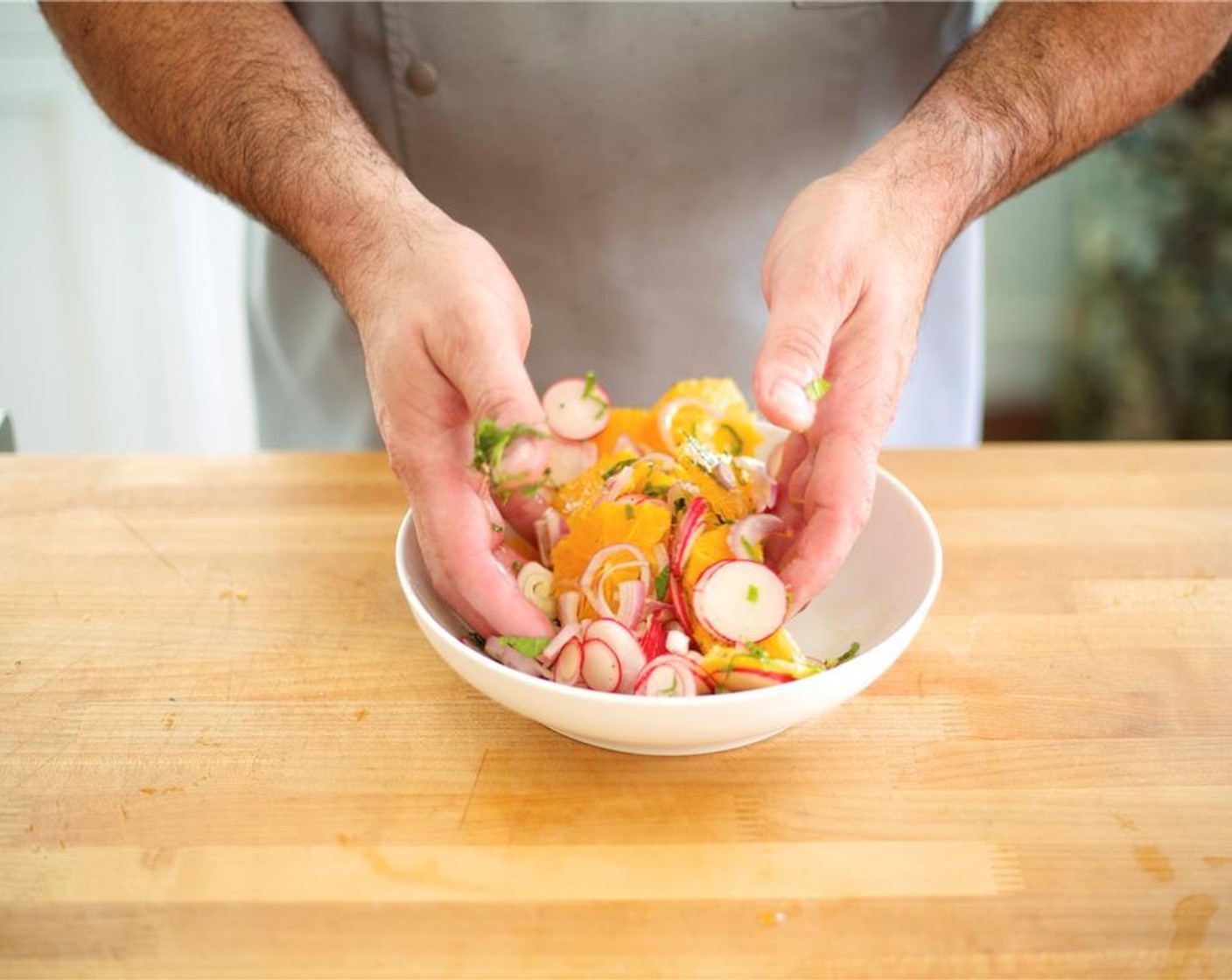 step 7 Cut the bottom and top off each Oranges (2). Stand the orange on one end and cut away the peel and pith with a small knife. Cut peeled orange into thin slices across, add to sliced shallot, mint, and radish in medium bowl. Add 1 tablespoon olive oil, 1/4 teaspoon salt and pepper