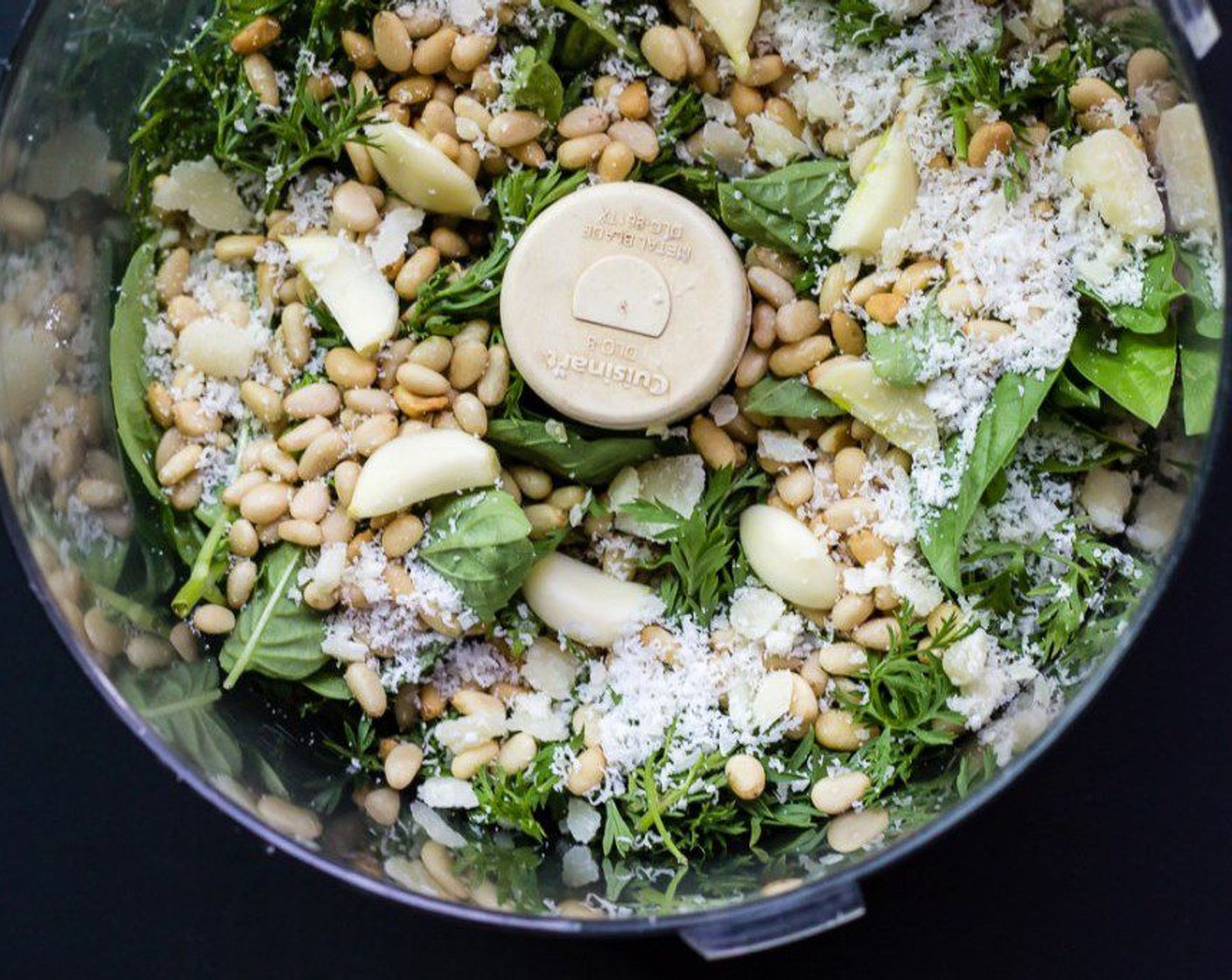 step 7 Add carrot leaves, Fresh Basil (1 handful), Garlic (1 clove), Pine Nuts (1/3 cup), Parmesan Cheese (1/3 cup), Olive Oil (1/2 cup), and Sea Salt Flakes (to taste) to bowl of a food processor.