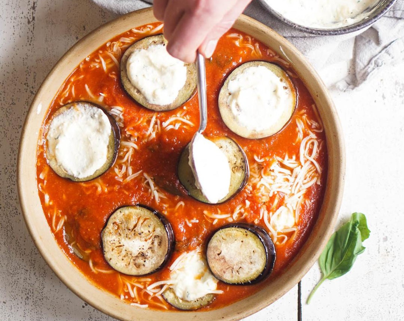 step 6 Spread 1/2 cup of the Tomato Sauce (2 3/4 cups) to the bottom of a 9x12 oval dish or 12" round dish. Arrange a layer of eggplant slices on top of the sauce, then top each slice with a heaping spoonful of ricotta cheese.
