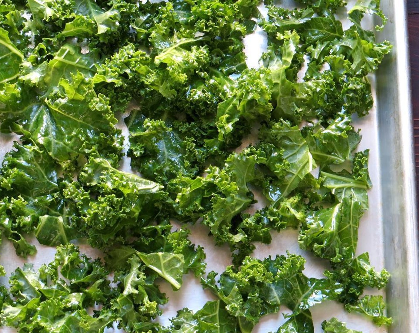 step 3 Place the dried kale in a bowl and toss to coat with Olive Oil (2 Tbsp). Spread it out onto a baking sheet lined with parchment paper.