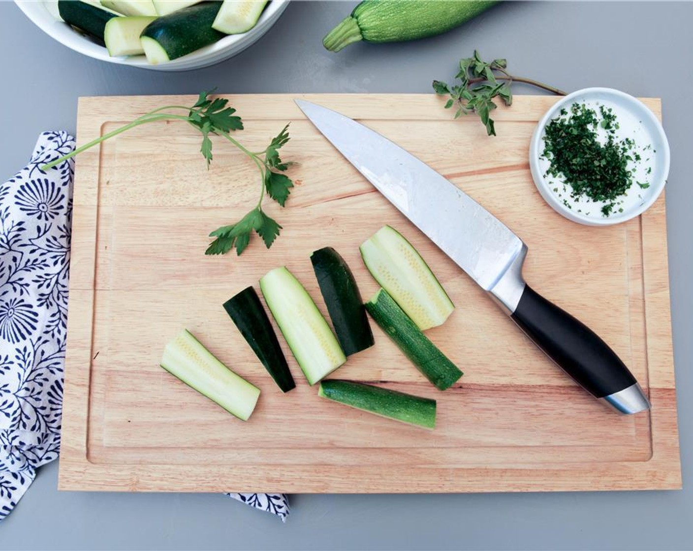 step 2 While the oven is preheating, wash and trim the tips of the Zucchini (3 1/2 cups). Then cut each in half lengthwise, and cut each of those pieces into halves. Next, finely chop the Italian Flat-Leaf Parsley (10) and Oregano Leaves (8).