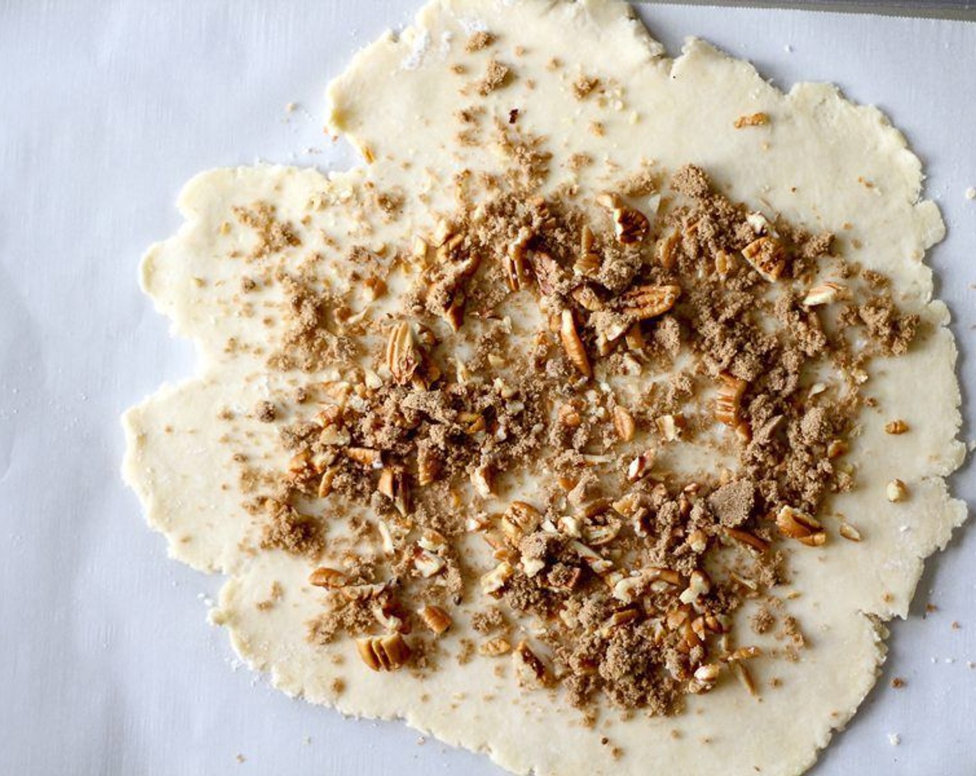 step 8 Transfer the dough circle to parchment-lined baking sheet. Sprinkle dough with the Pecans (4 Tbsp) and Brown Sugar (2 Tbsp), leaving 1/2 inch bare.