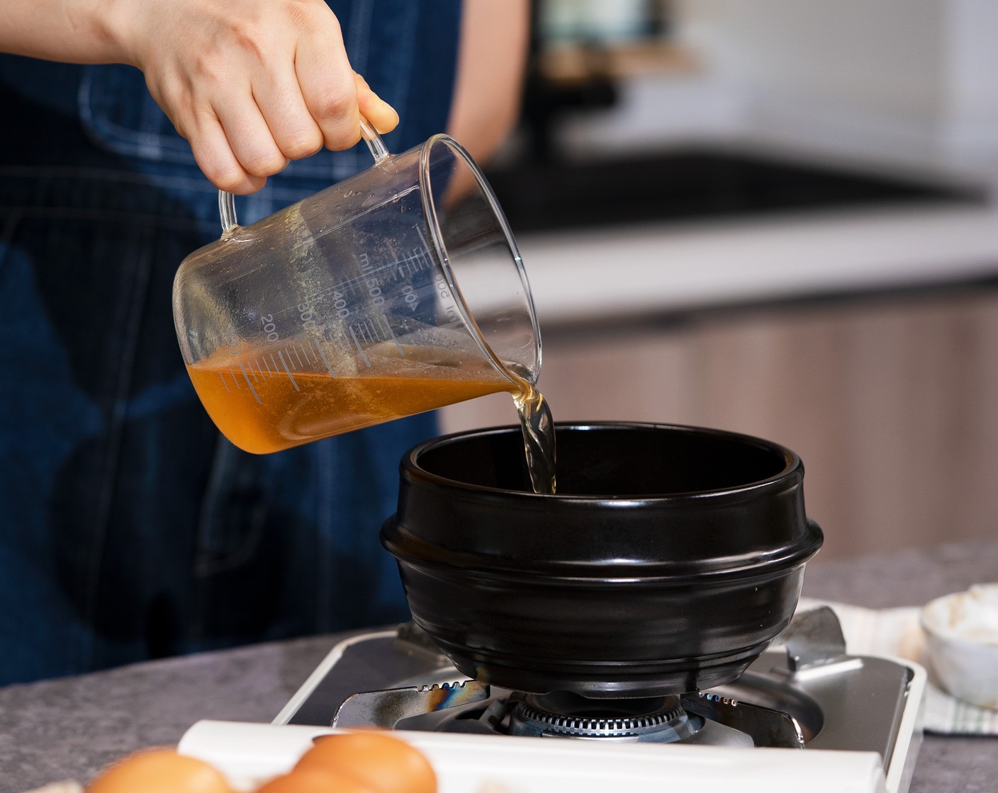 step 2 Brush an earthen pot with Sesame Oil (1/2 tsp). Place on the stovetop, pour in Vegetable Broth (1 1/4 cups), then boil over medium-high heat.