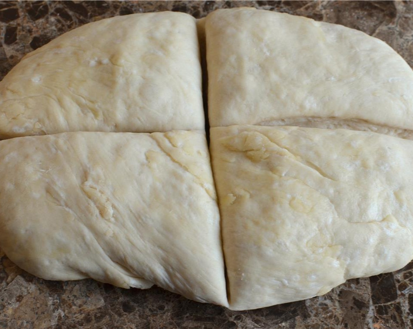 step 6 Once the dough has risen, turn it out onto a lighly floured surface and divide it into 4 quarters.