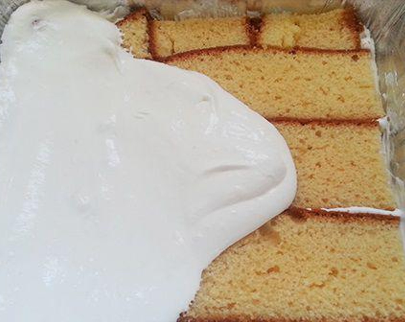 step 3 Take a pudding tray and spread little whipped cream on the bottom. Now keep a layer of the cake. Spread a layer of whipped cream on the cake layer. Make sure the cake pieces are well covered.