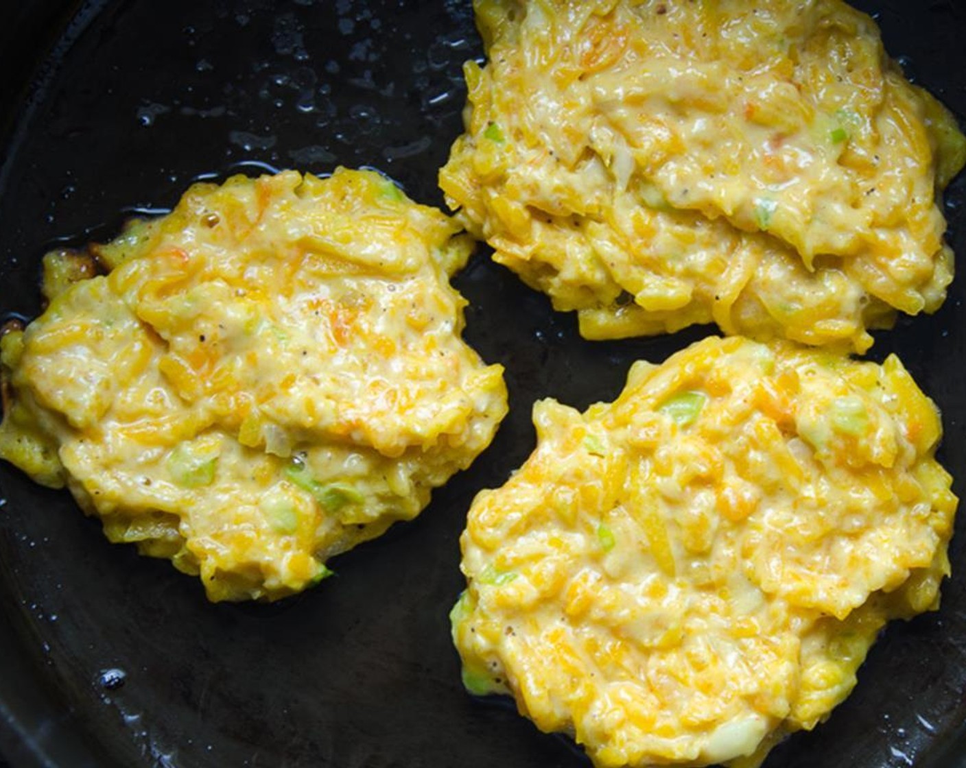 step 7 In a heavy bottomed skillet, heat the Olive Oil (2 Tbsp) and Canola Oil (2 Tbsp)until very hot, but not smoking. Spoon heaping tablespoons of butternut squash batter into the pan and flatten with the back of a spoon.