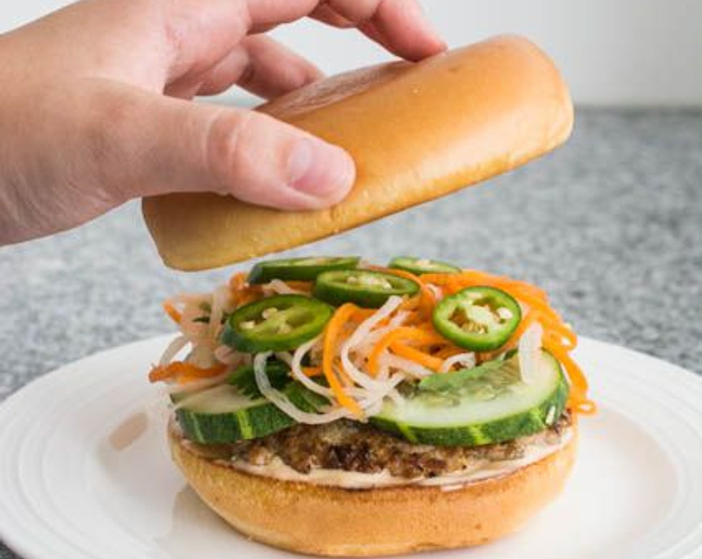 step 11 Top with Cucumbers (12 slices), Fresh Basil Leaves (2 cups), Fresh Cilantro (1 1/2 cups), pickled carrot and daikon radish, Jalapeño Pepper (1), then the top burger bun.