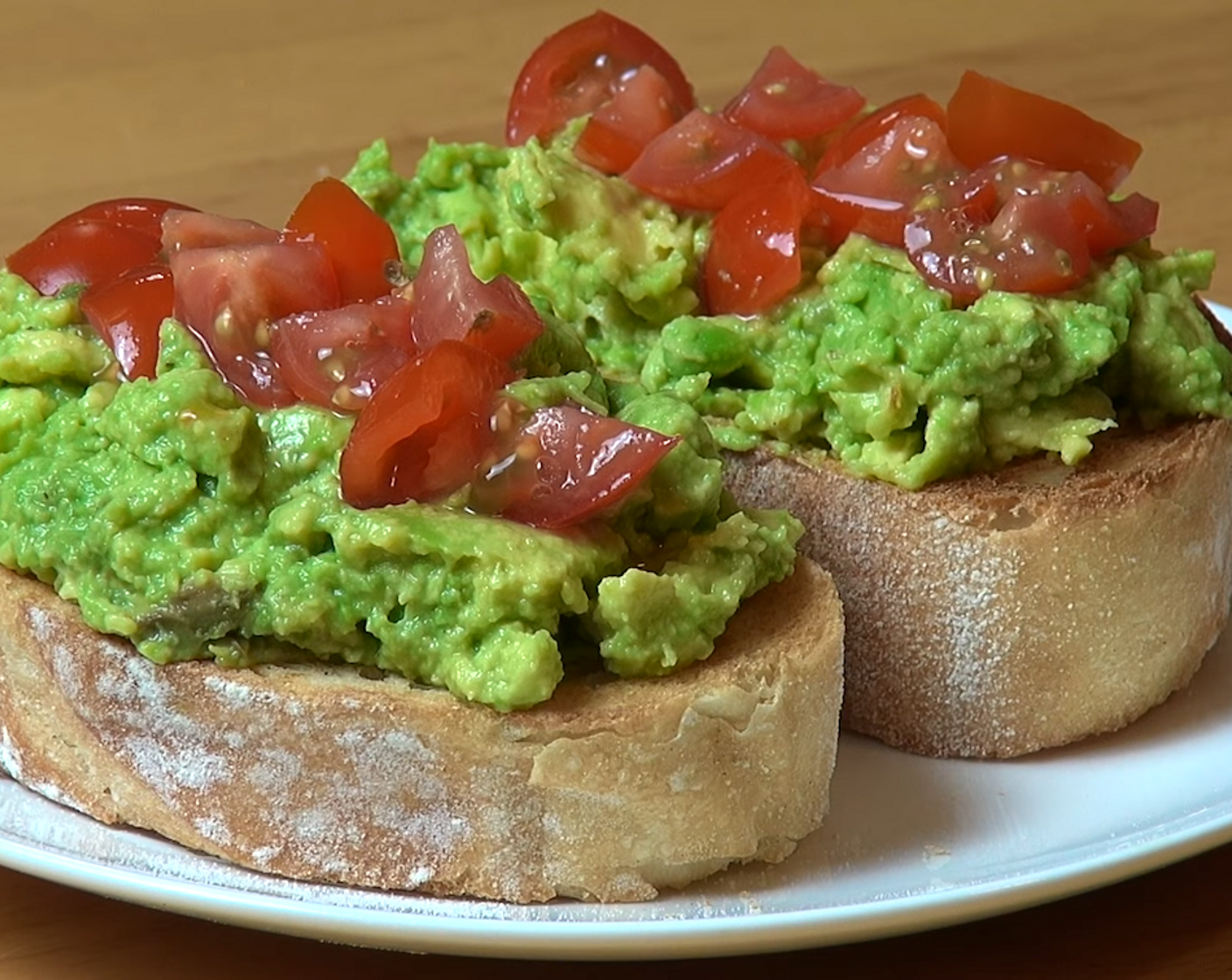 step 2 Carefully spoon the avocado on each piece of Bread (2). Add the Tomatoes (to taste) or any topping of your choice on top and serve!