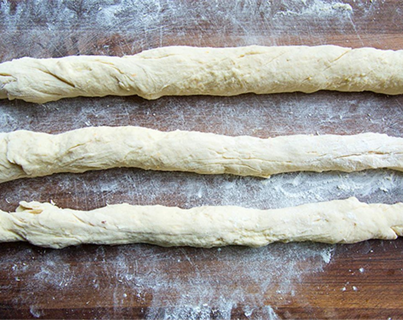 step 6 Punch the dough down and knead for another couple of minutes. Divide into 3 equal pieces. Roll each piece into a 20 inch long rope.