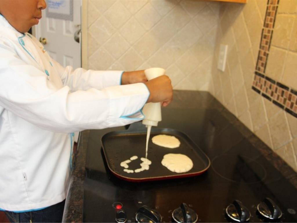 Step 4 of Three Layer Strawberry Pancakes Recipe: Spray a griddle or frying pan with cooking spray and add a small circle of pancake batter onto the hot pan.