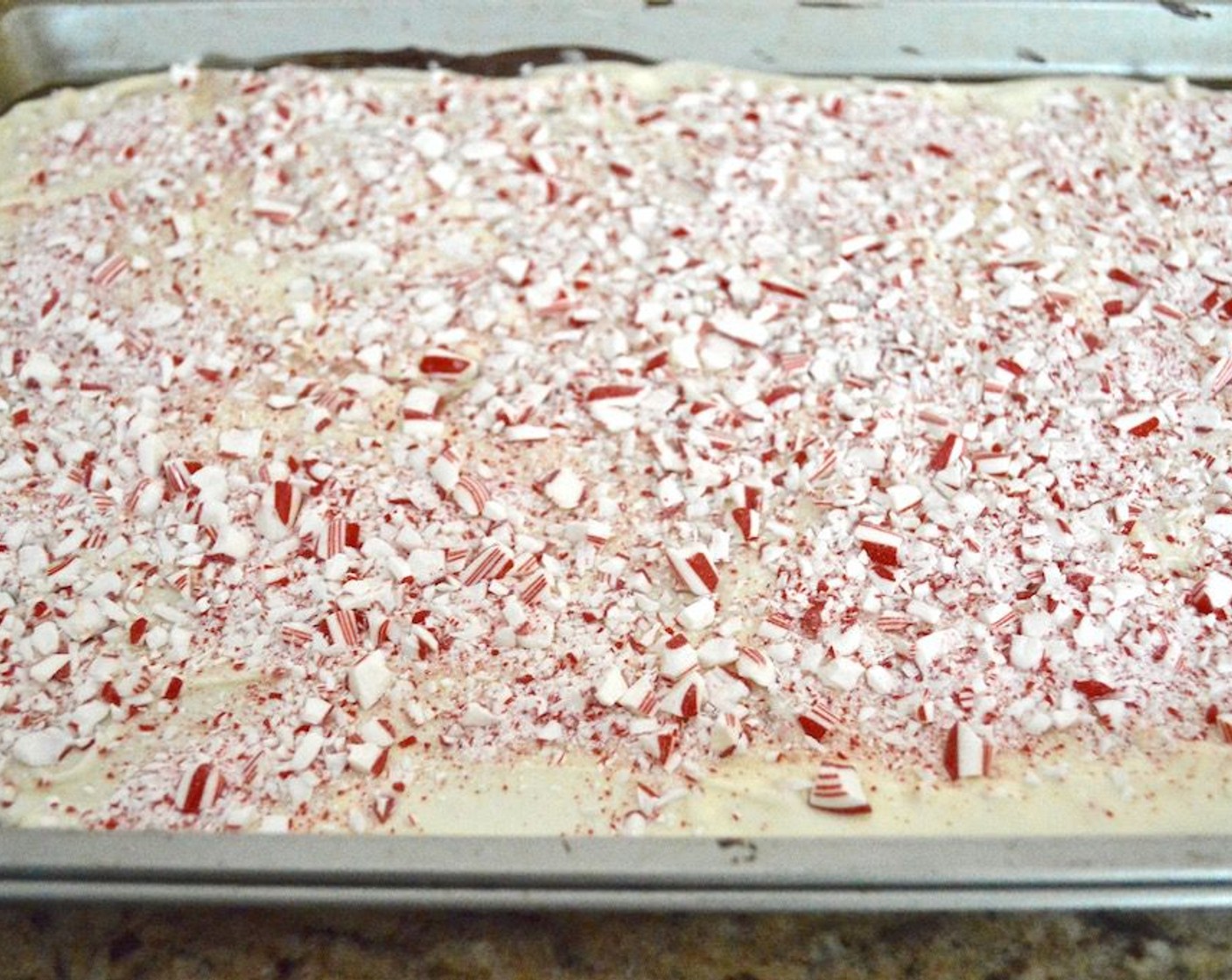 step 8 Pour the white chocolate over the dark chocolate and gently smooth it out to be even. Quickly sprinkle the remaining crushed candy cane on top.